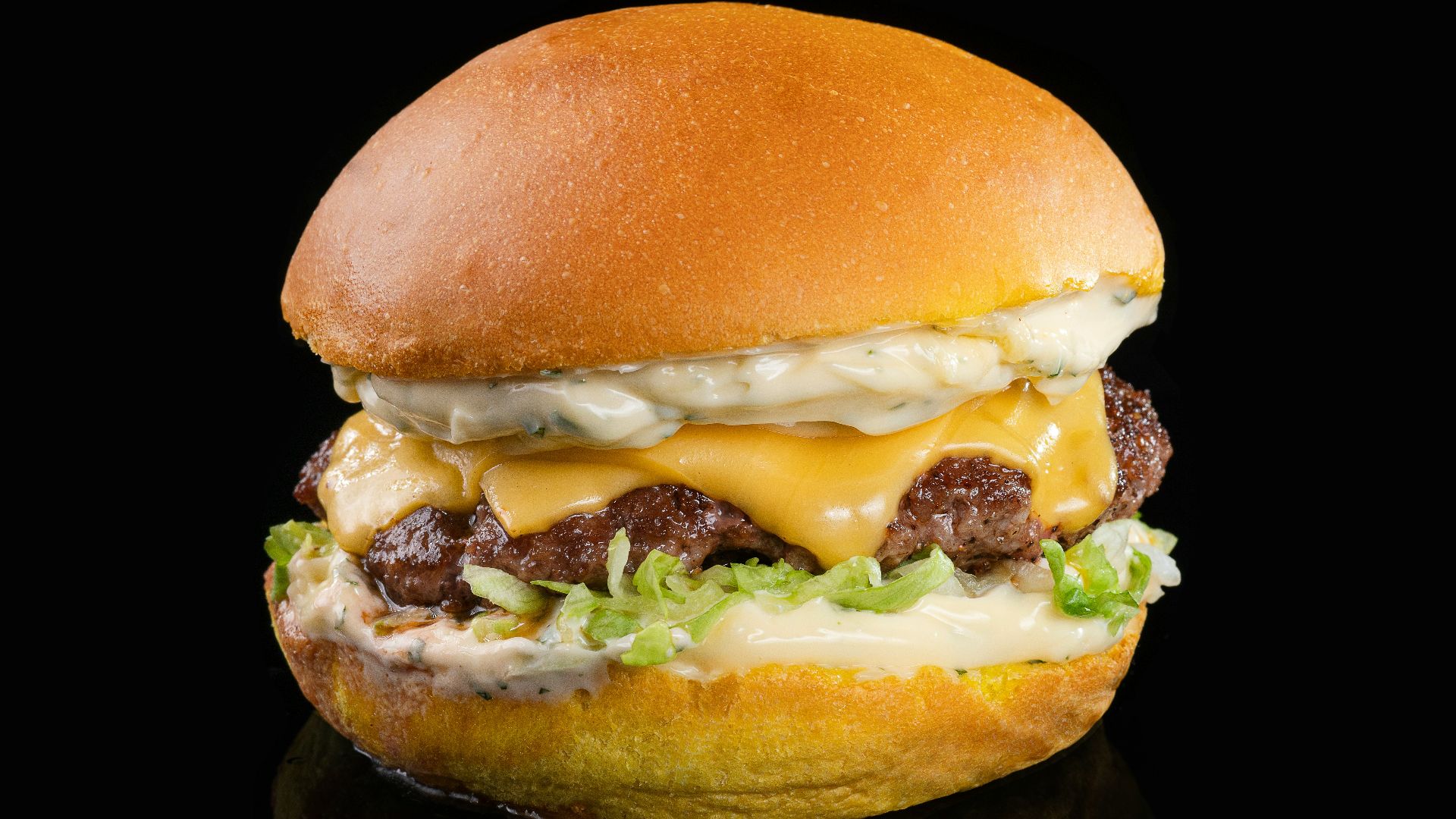 a cheeseburger with meat and lettuce on a black background