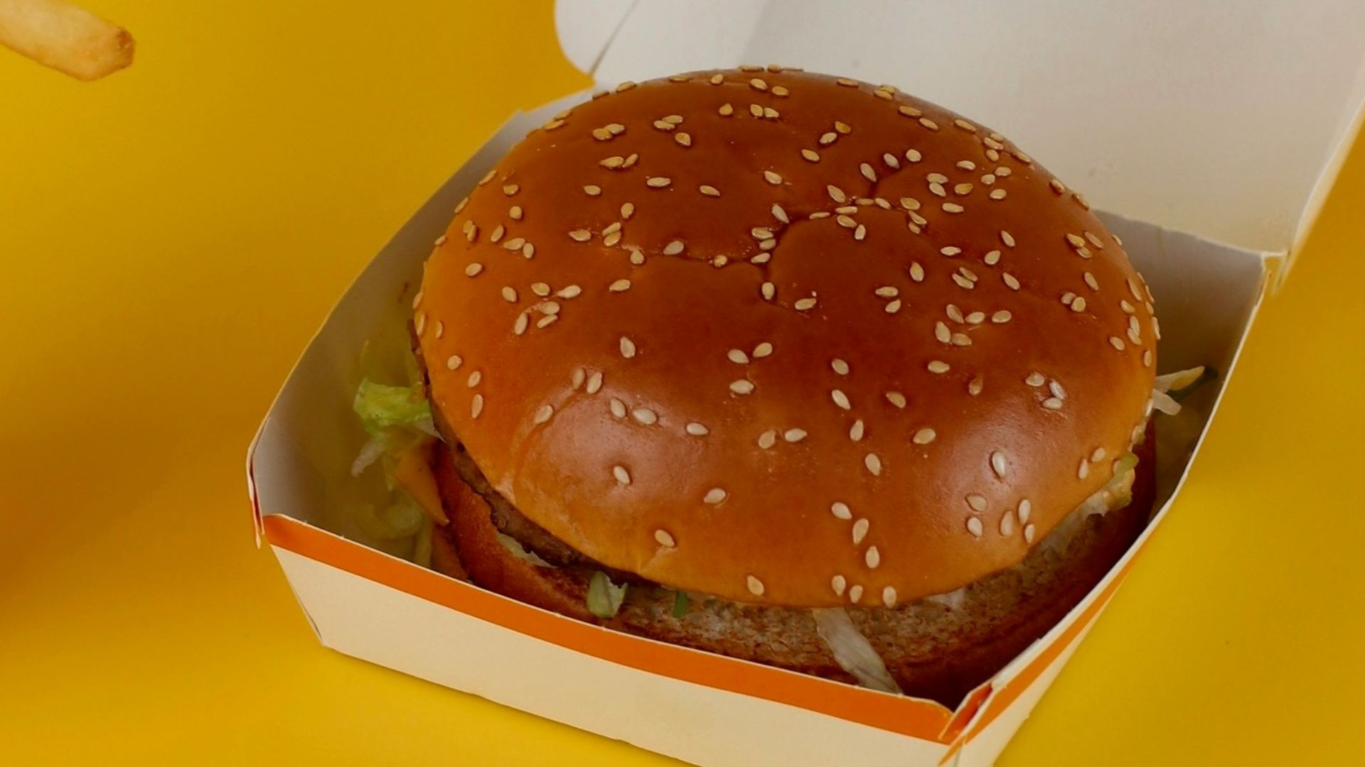 a mcdonald's hamburger and french fries on a yellow background