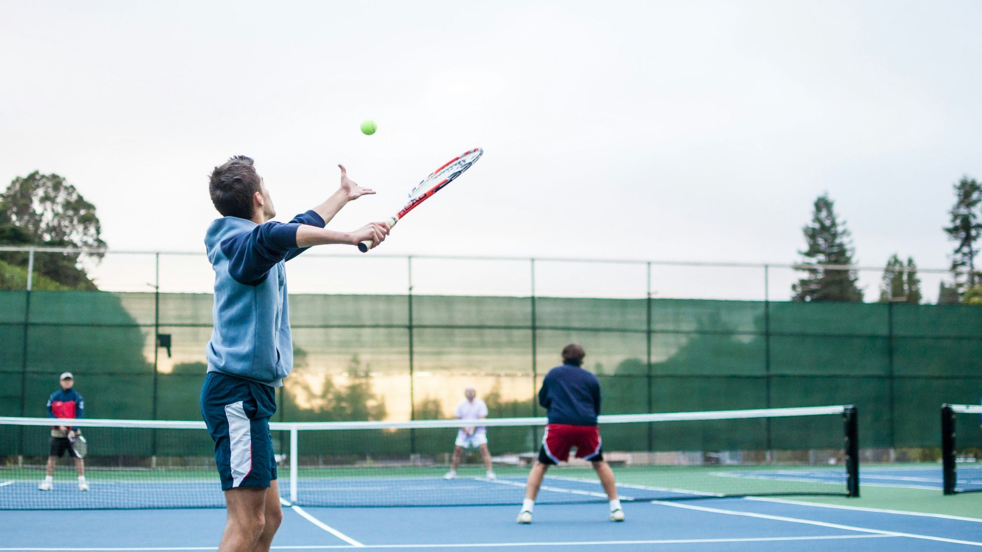four men playing double tennis during daytime