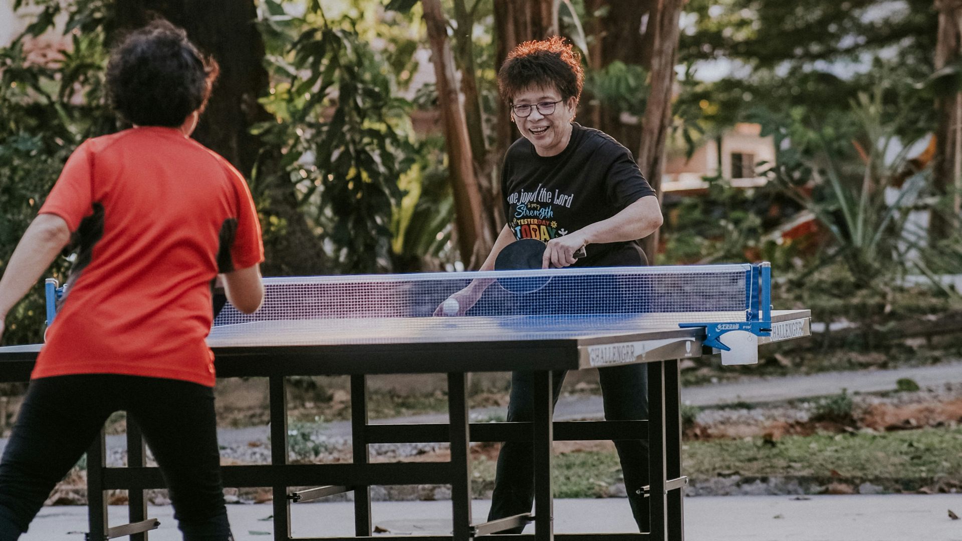 man in red crew neck t-shirt standing beside blue table during daytime
