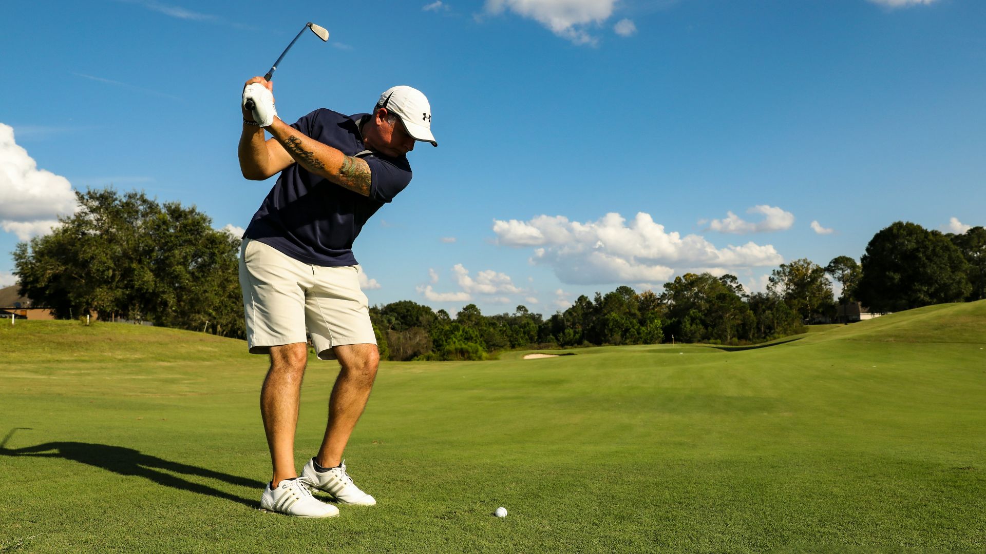 man in black shirt and white shorts playing golf during daytime