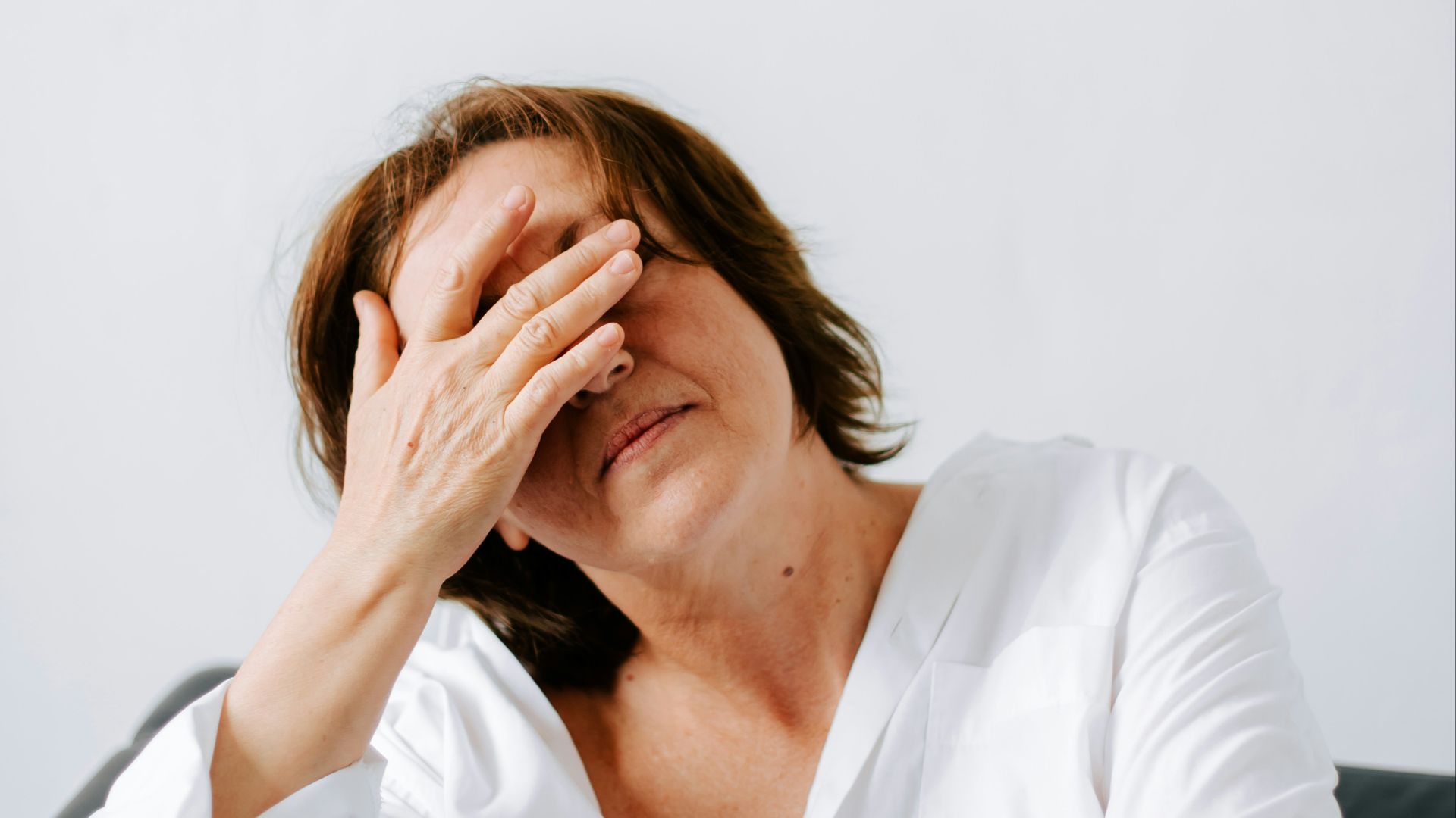 a woman sitting on a couch holding her hands to her face