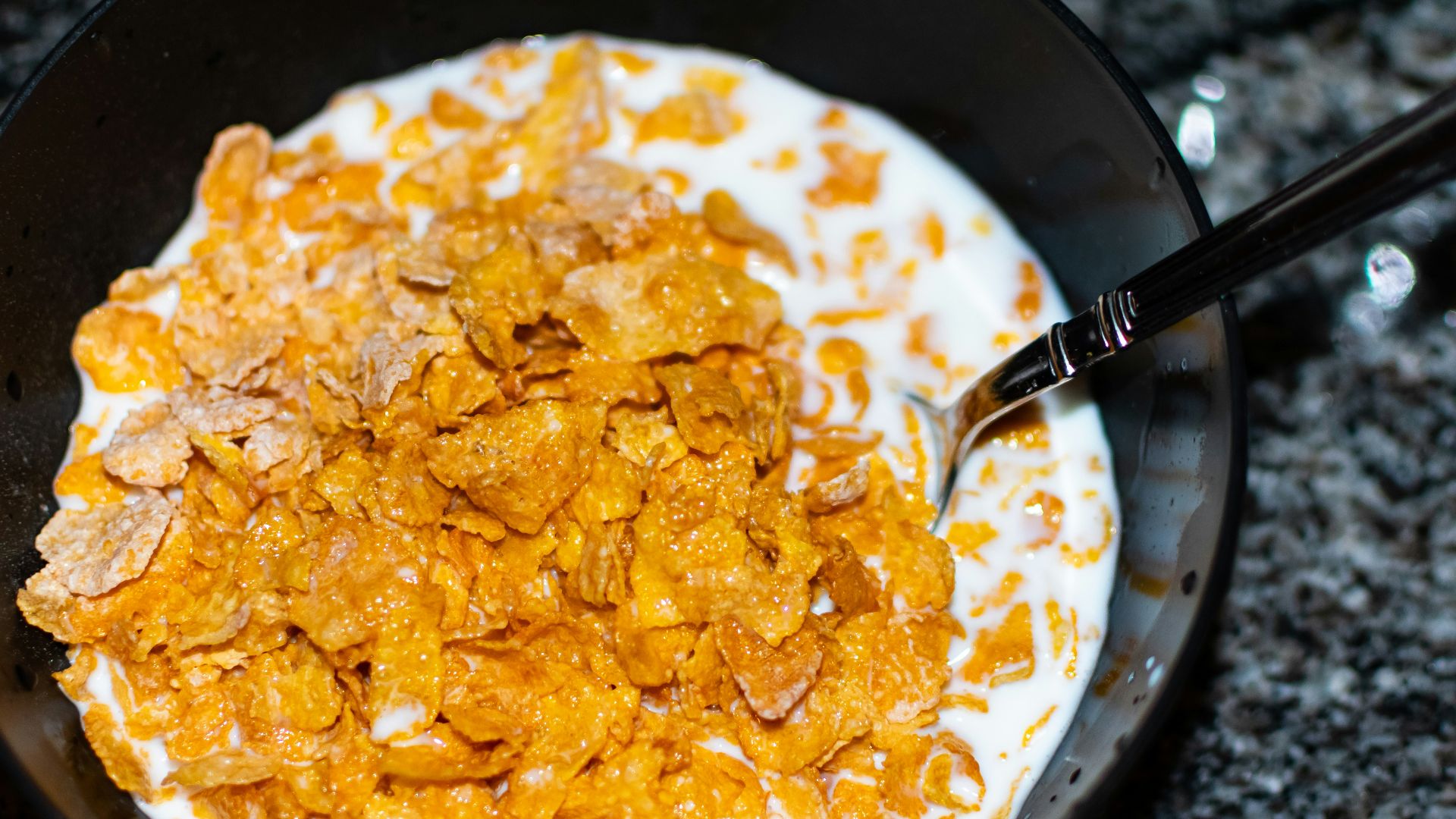 Cornflakes and milk sit in a bowl.