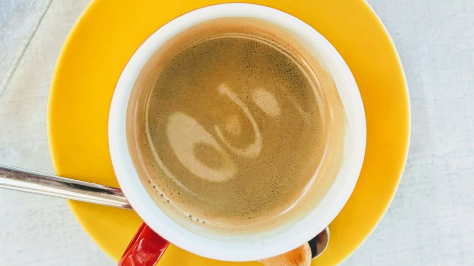 white ceramic mug with coffee on yellow saucer