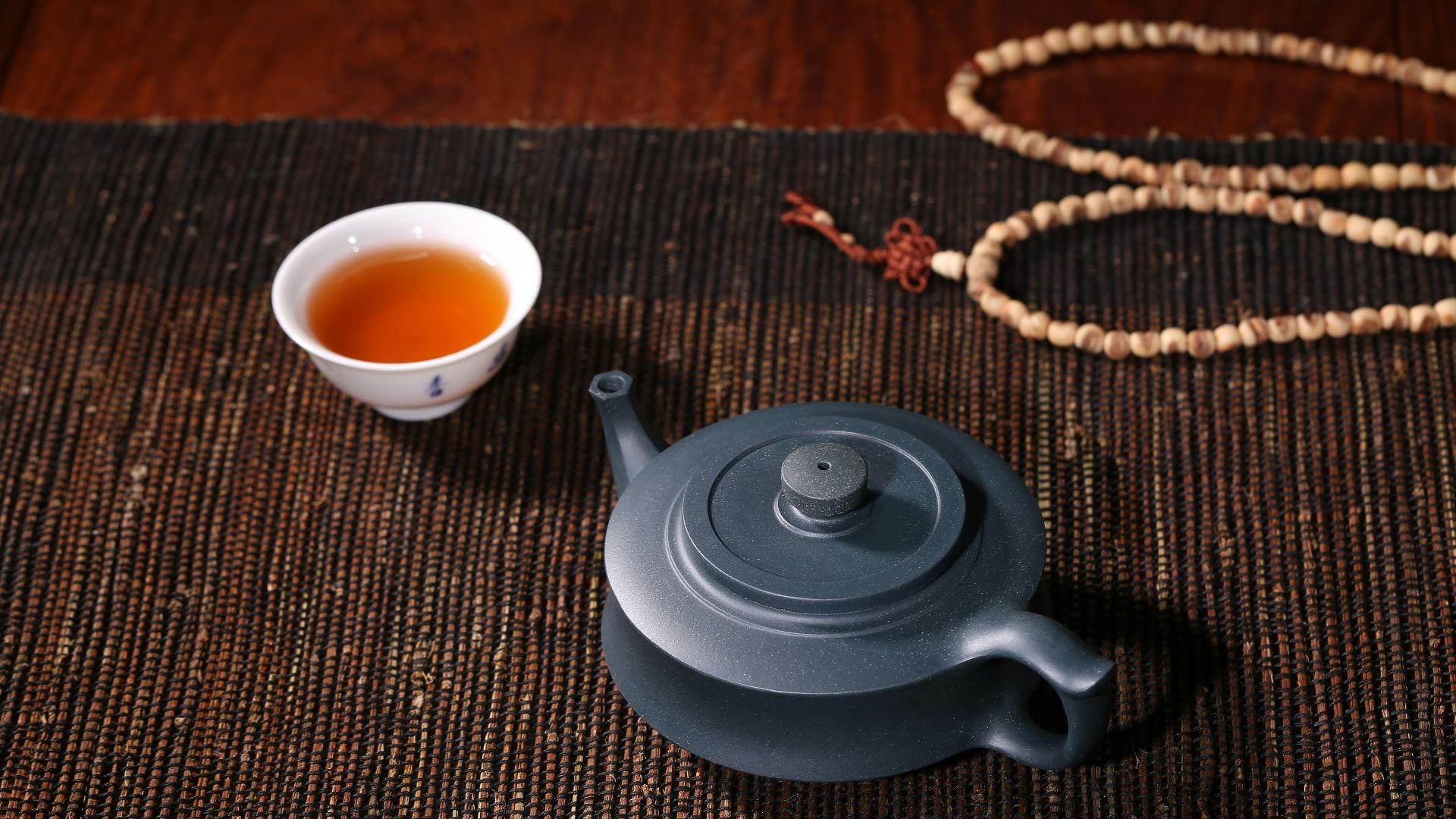 white ceramic teacup beside black ceramic teapot