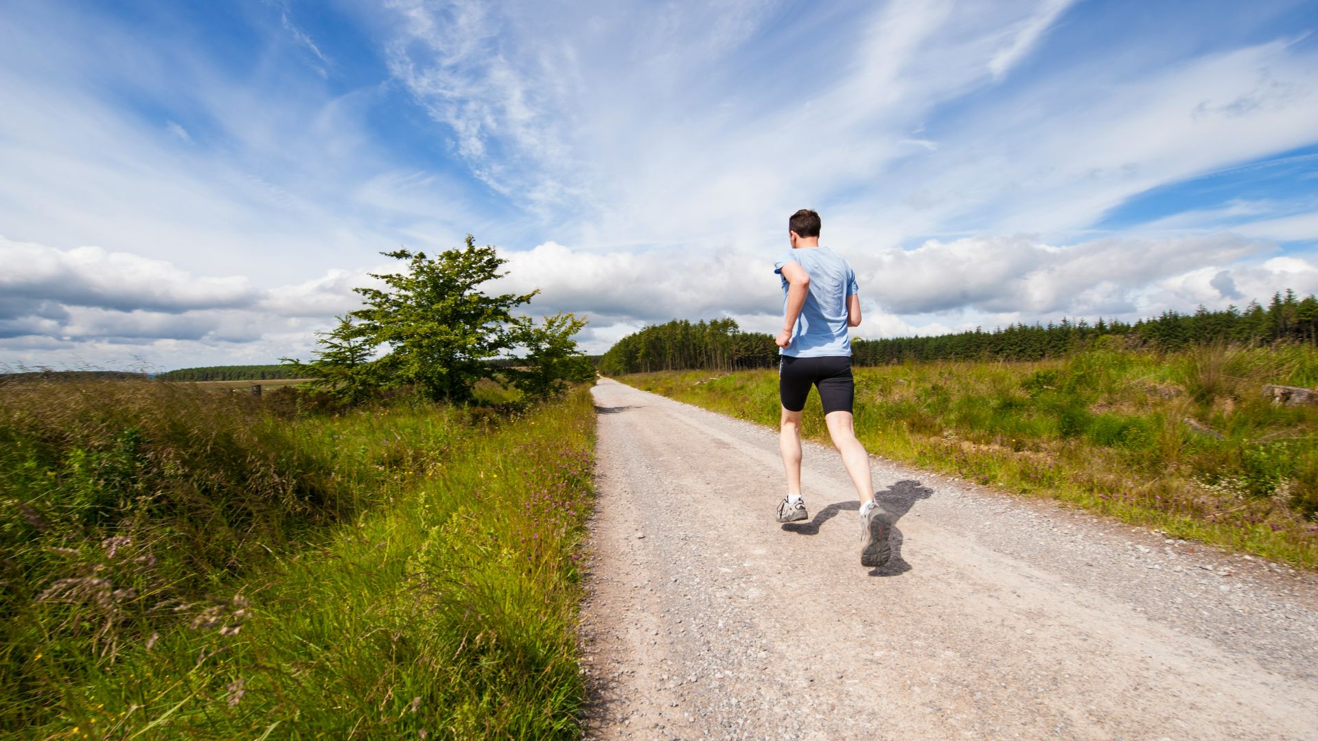 man running on road near grass field