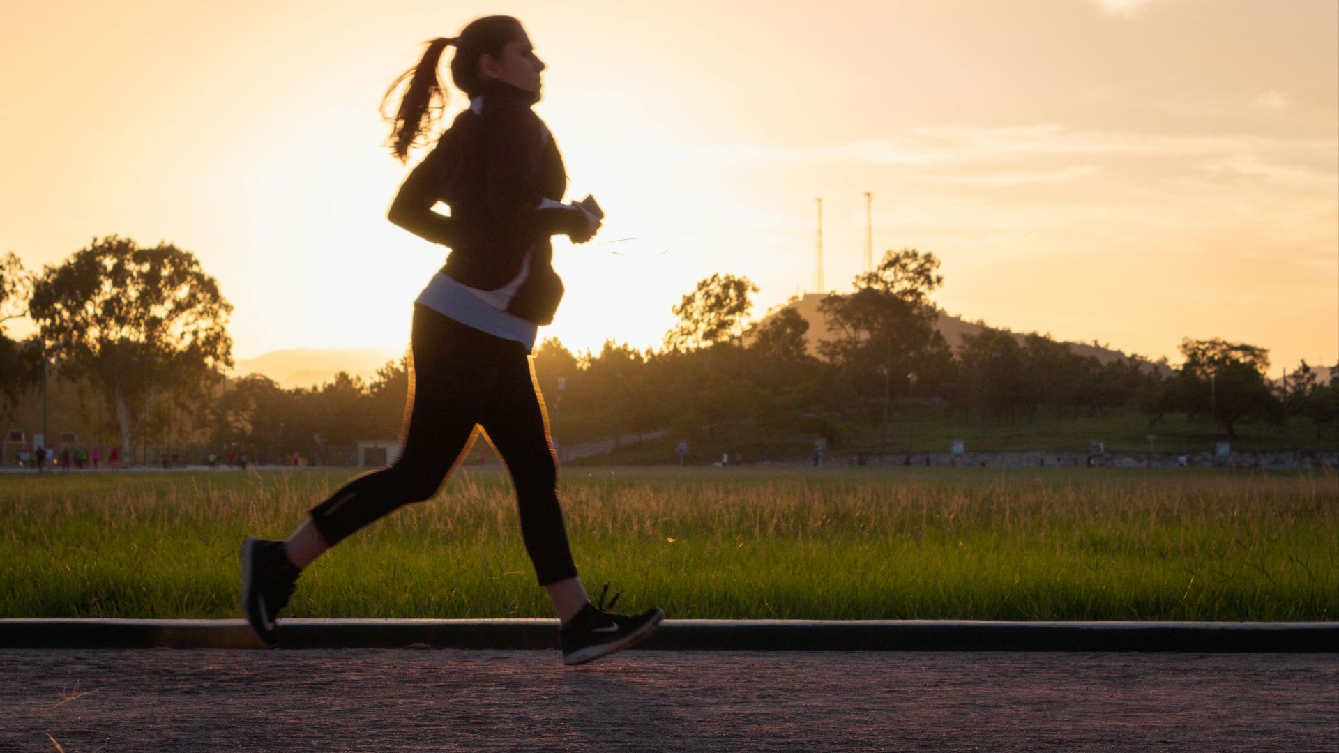 woman in black sports bra and black pants running on water during sunset