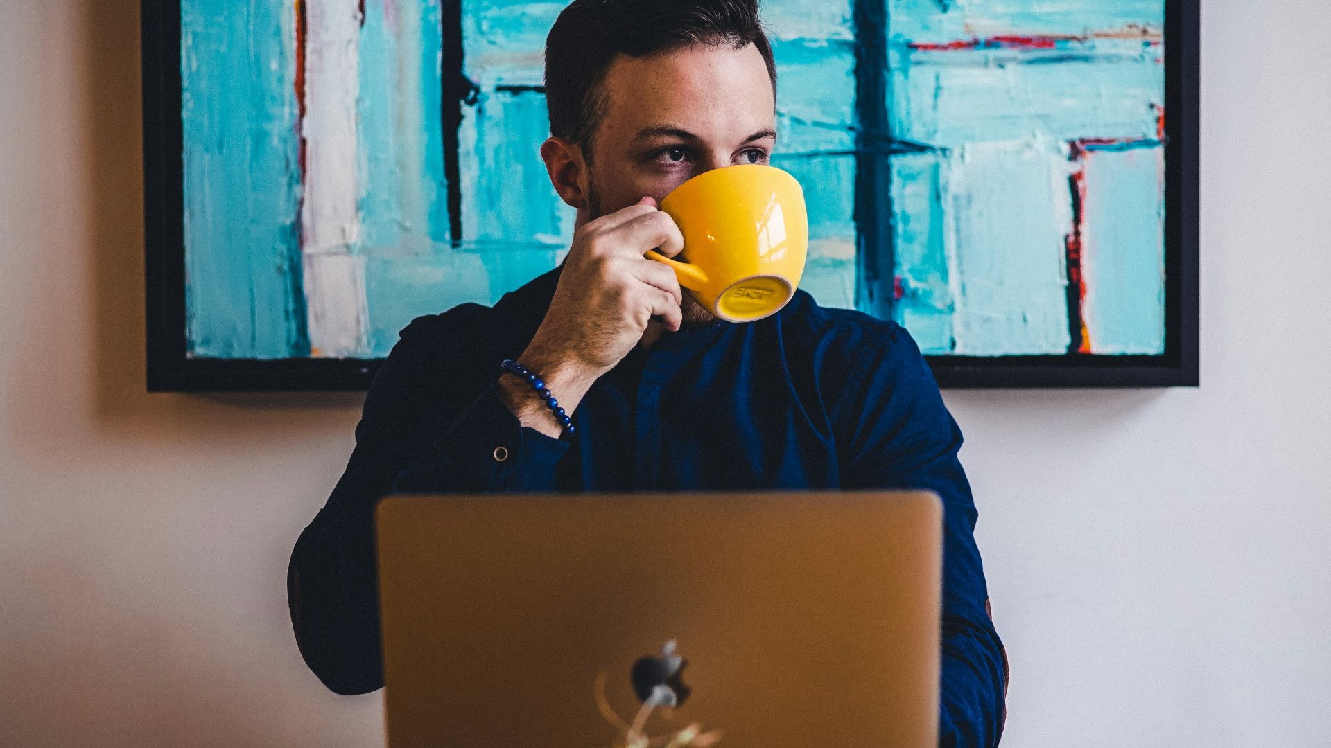 man drinking coffee in front of the laptop computer