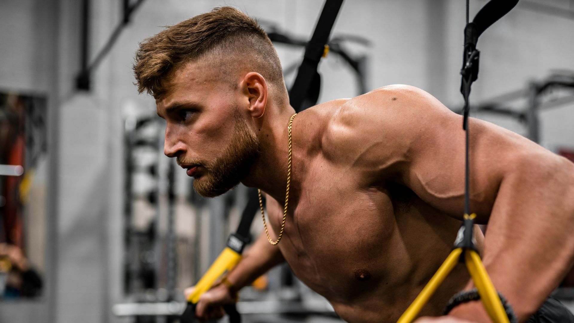 topless man in black pants holding black and yellow exercise equipment