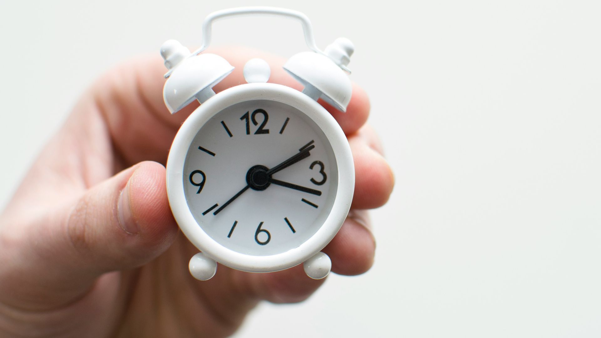 person holding white mini bell alarmclock