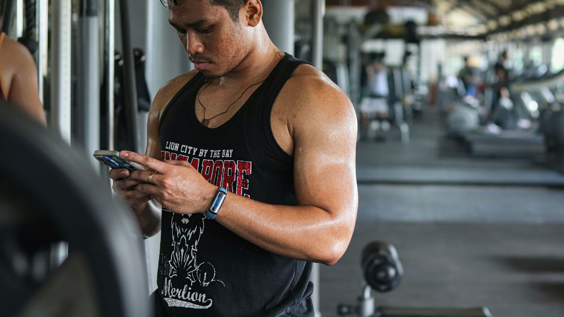 A man in a gym looking at his cell phone