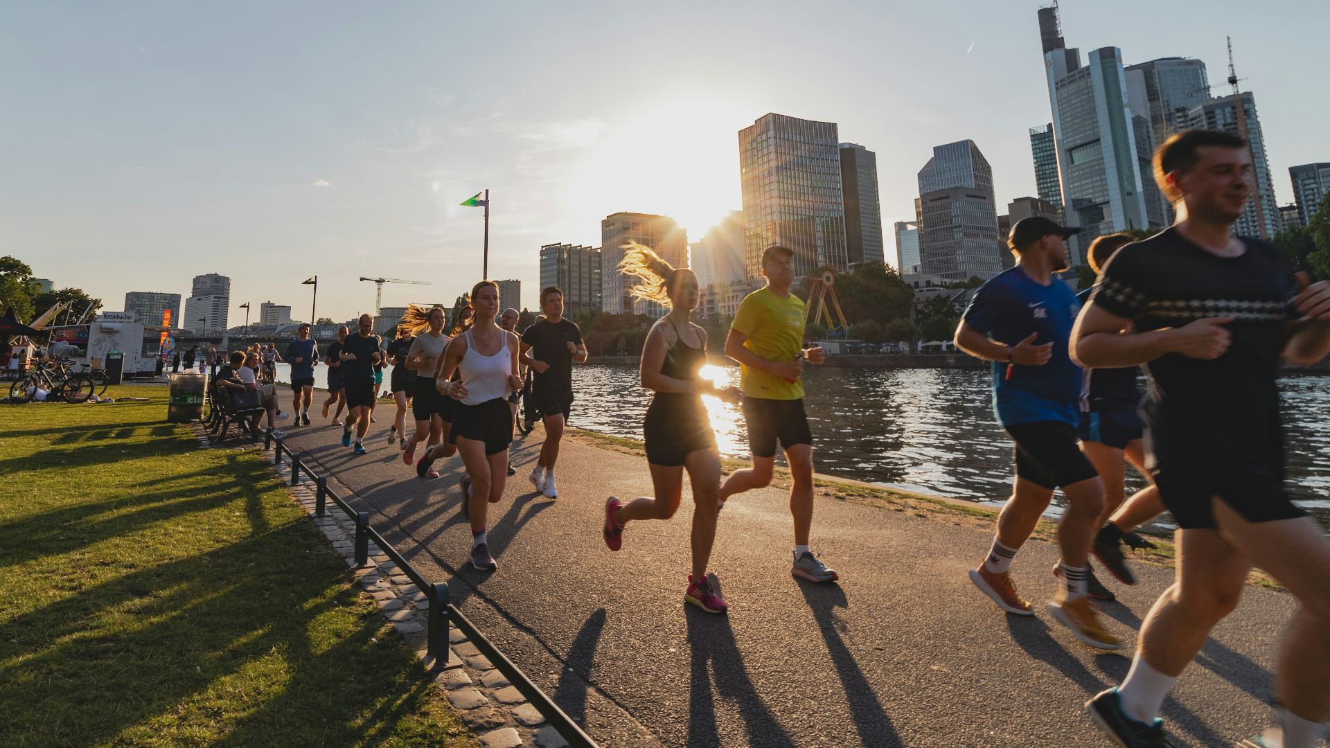 A group of people running down a street next to a river