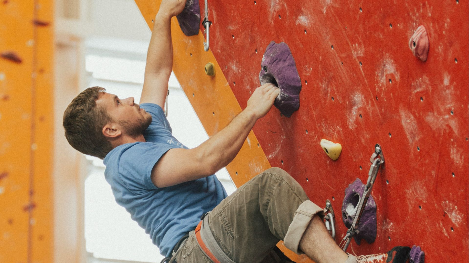 man wall climbing on red wall