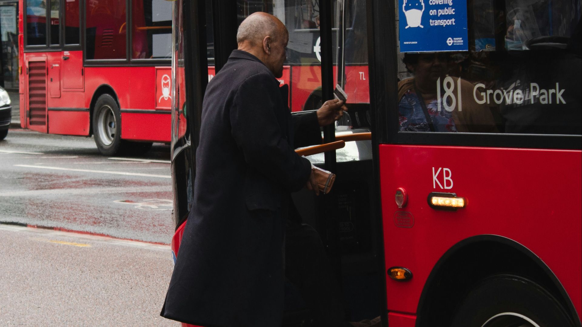 man in black coat standing beside red bus during daytime