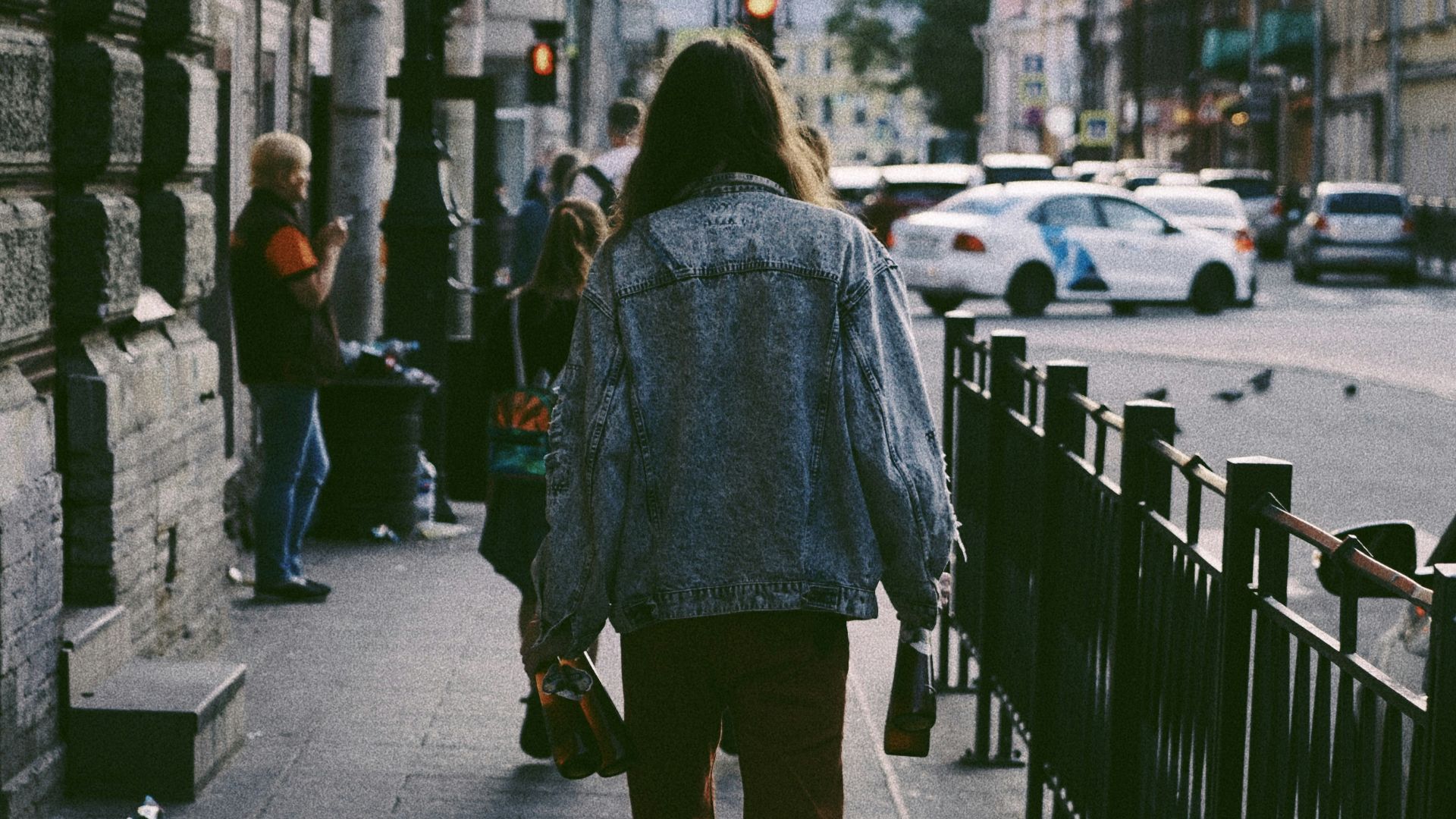 person wearing blue jacket walking on sidewalk