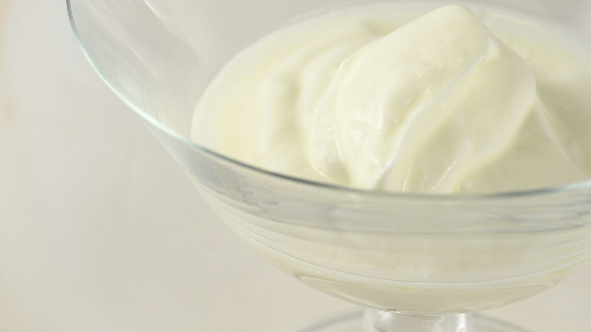 a glass bowl filled with cream on top of a table