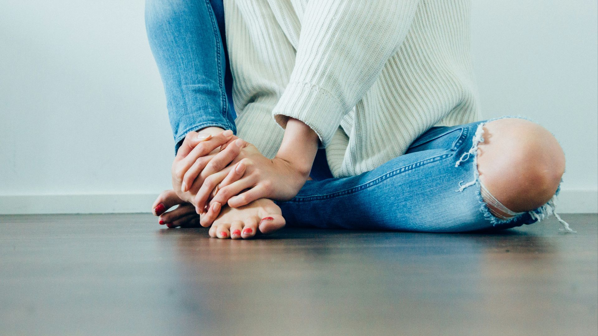 person wearing distressed blue denim jeans inside room