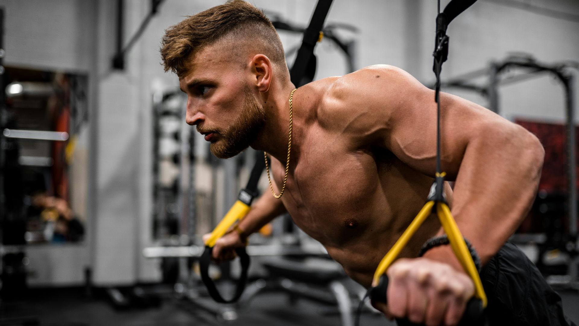 topless man in black pants holding black and yellow exercise equipment