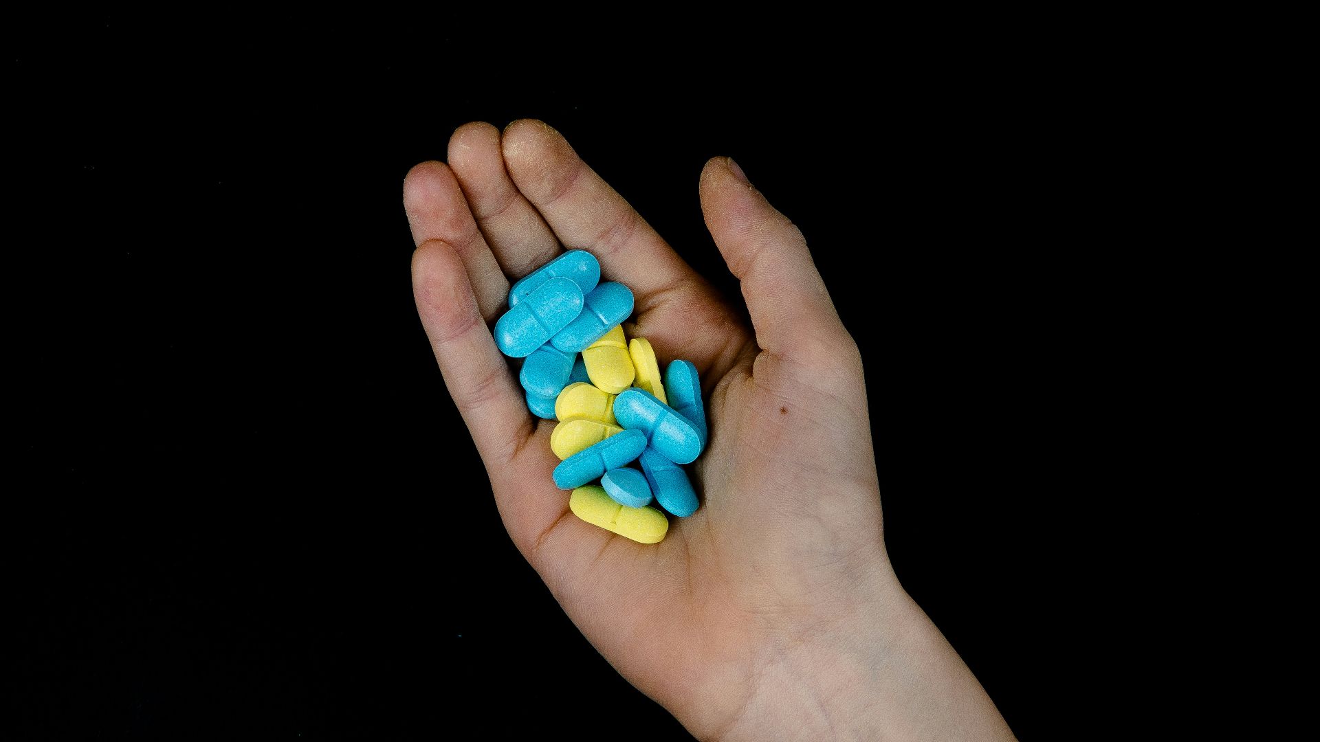 a person's hand holding a handful of pills