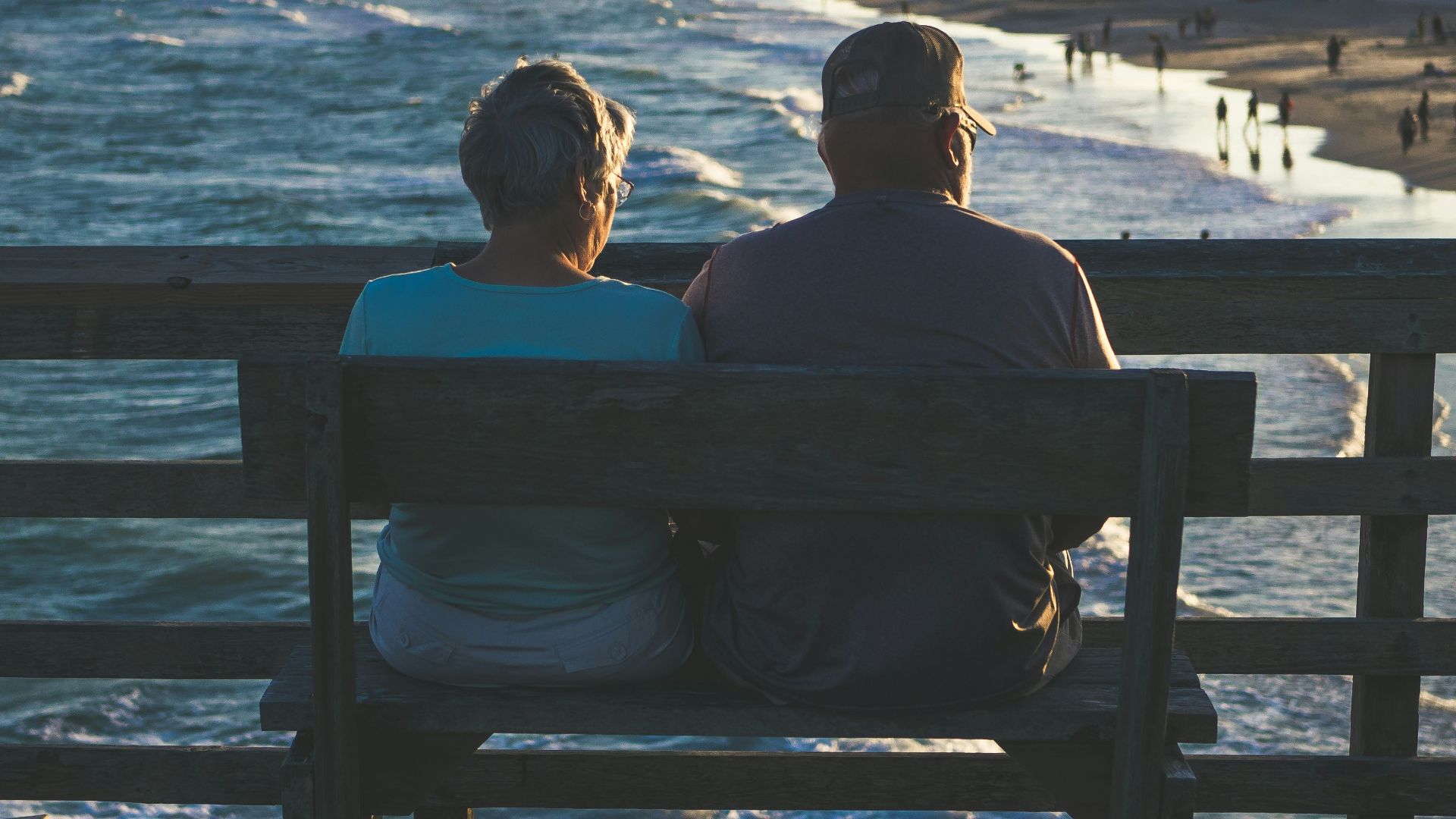 man and woman sitting on bench in front of beach