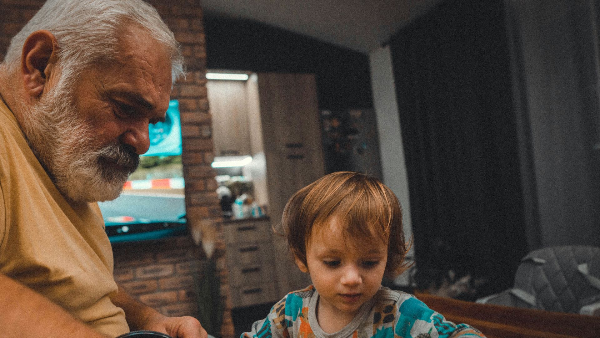 an older man and a young boy playing with a toy car