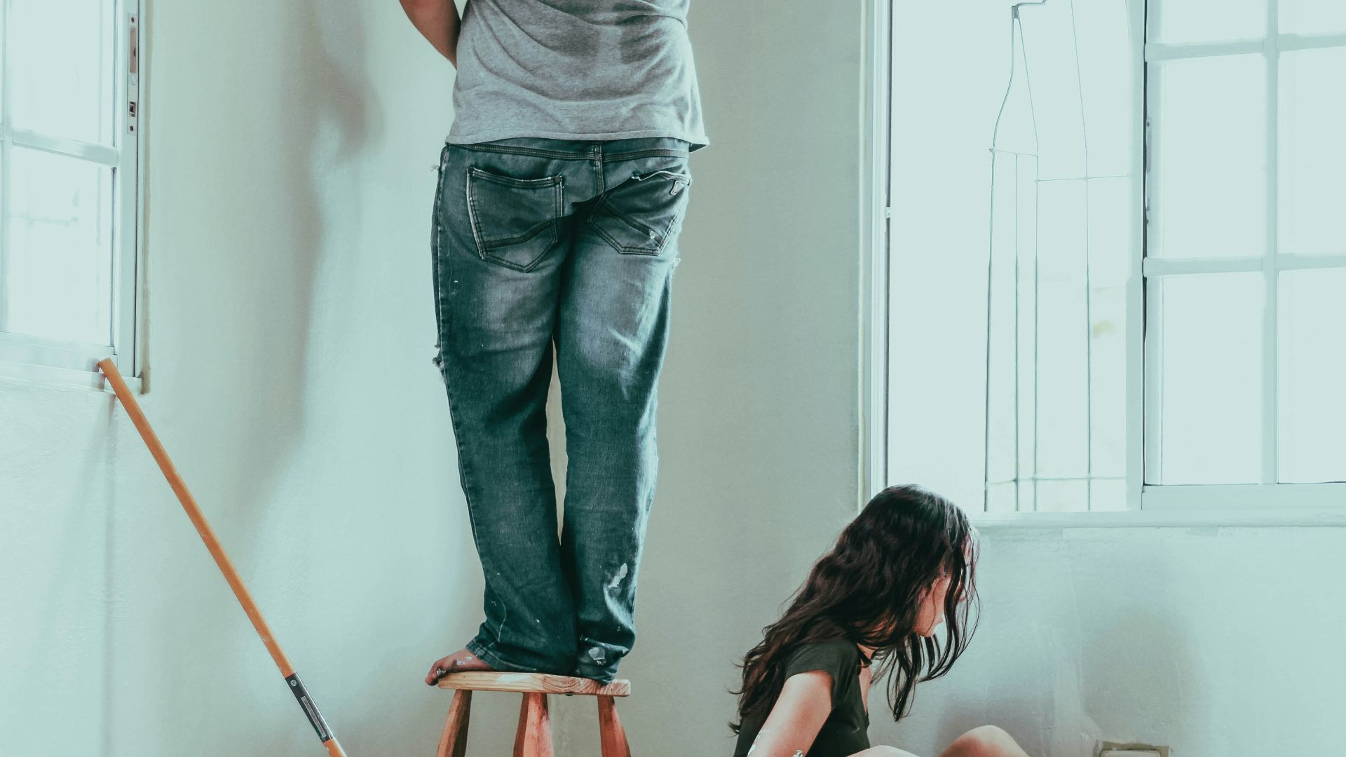 woman in gray tank top and blue denim jeans sitting on bed