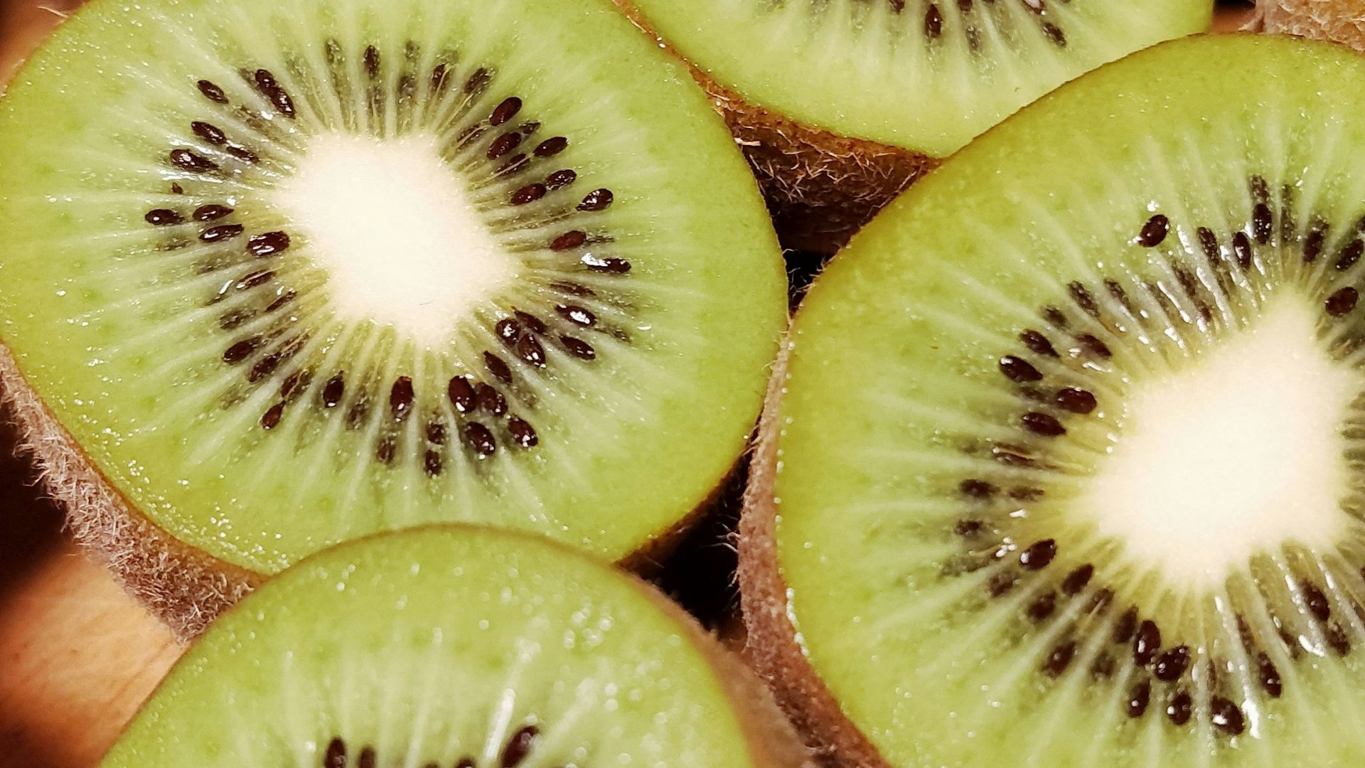 a bunch of kiwi cut in half on a cutting board