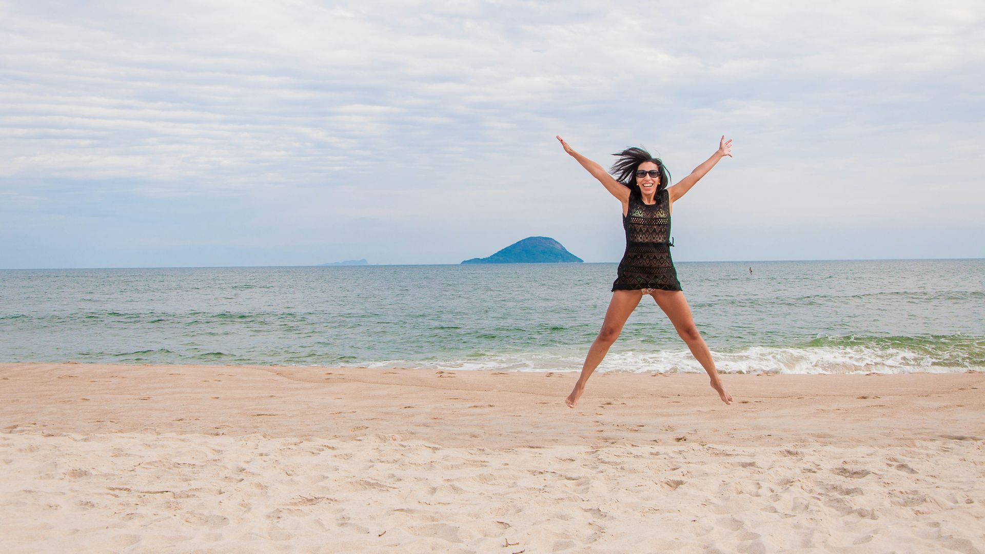 woman in black dress standing on beach during daytime