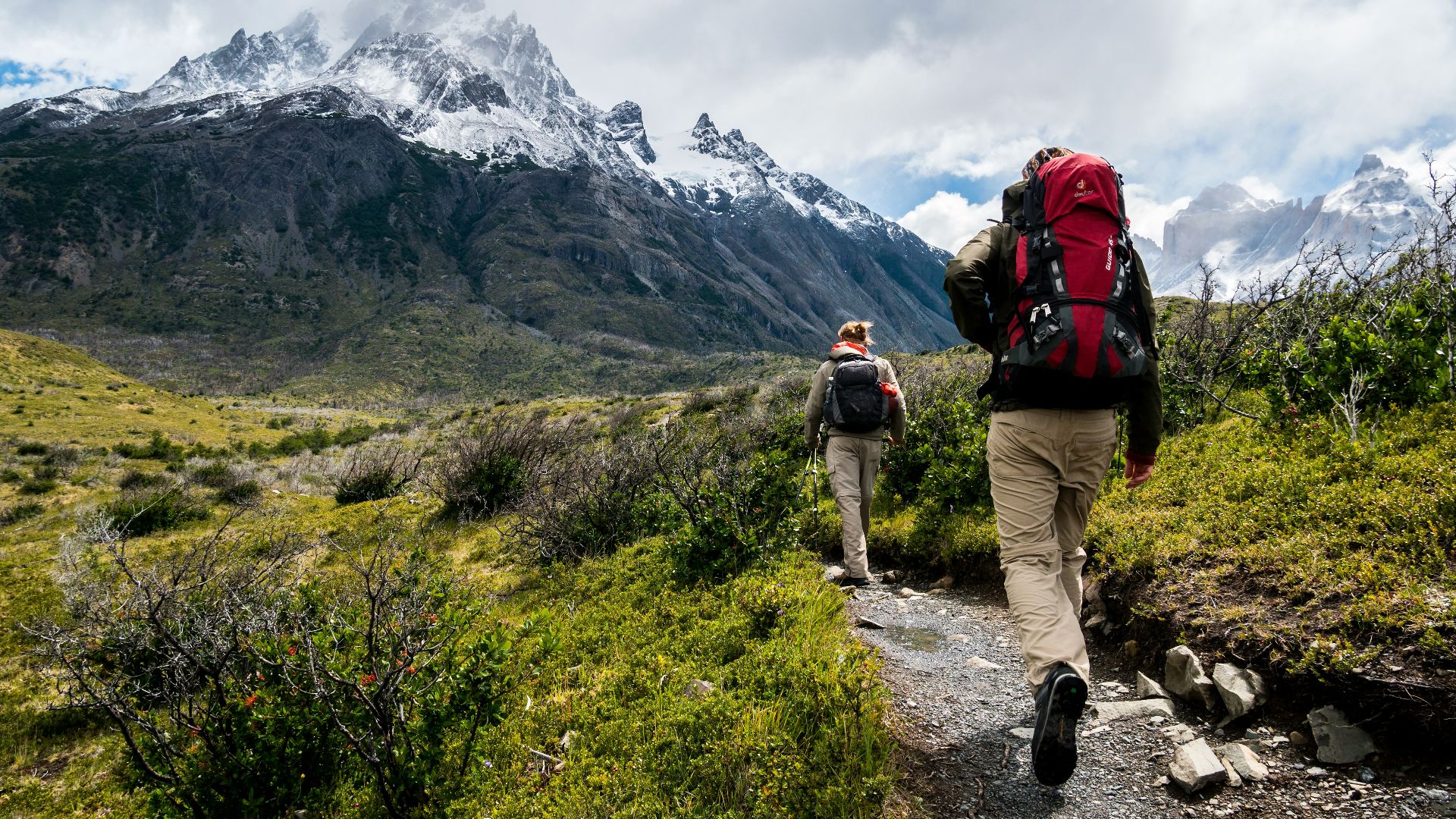 two person walking towards mountain covered with snow