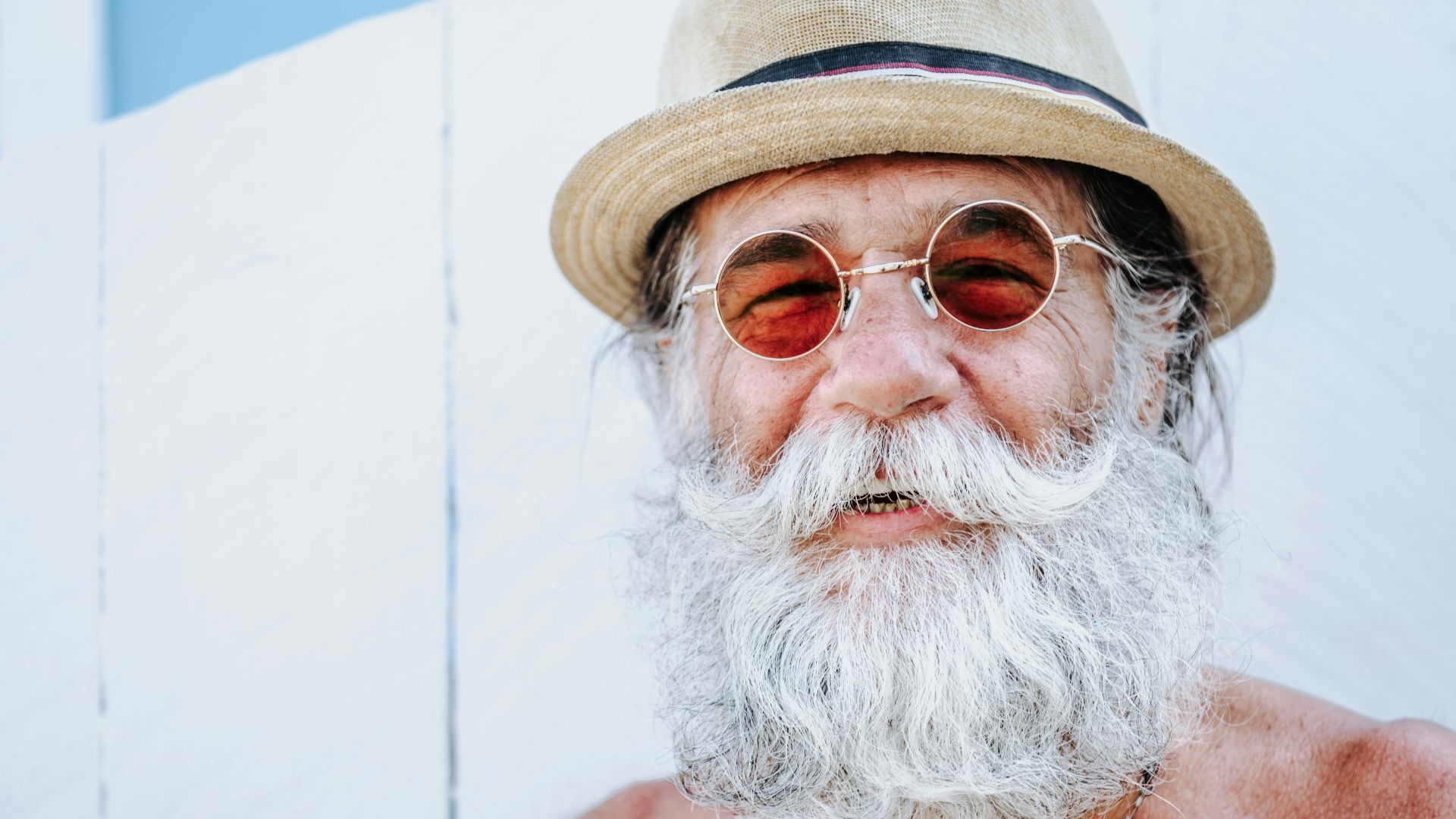 a man with a white beard and mustache wearing a hat