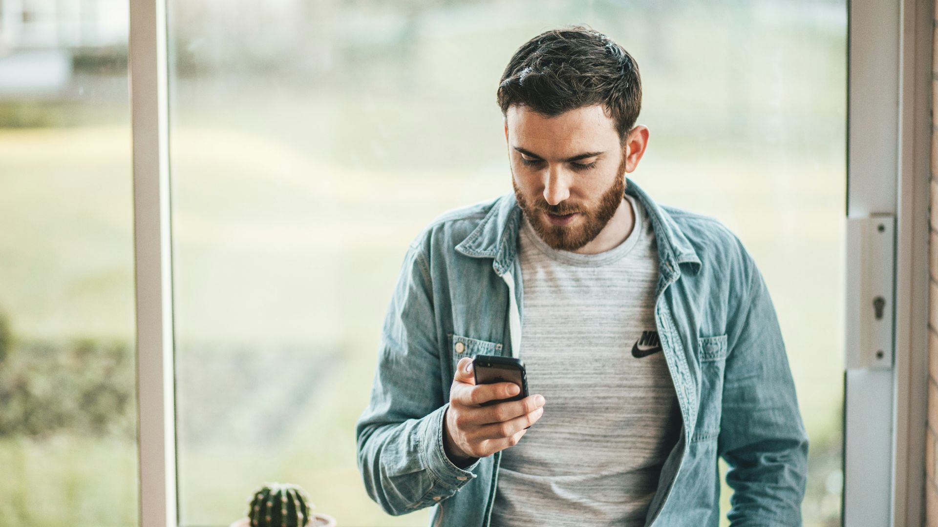 man holding a smartphone near the window