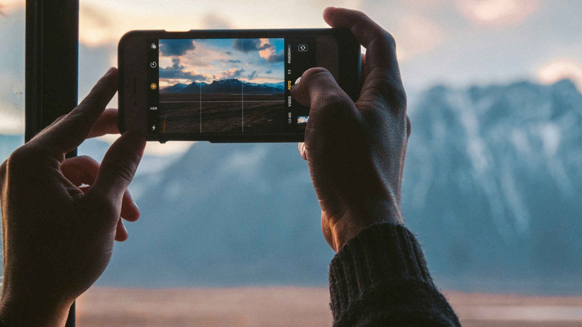 person holding black smartphone taking photo of mountain during daytime