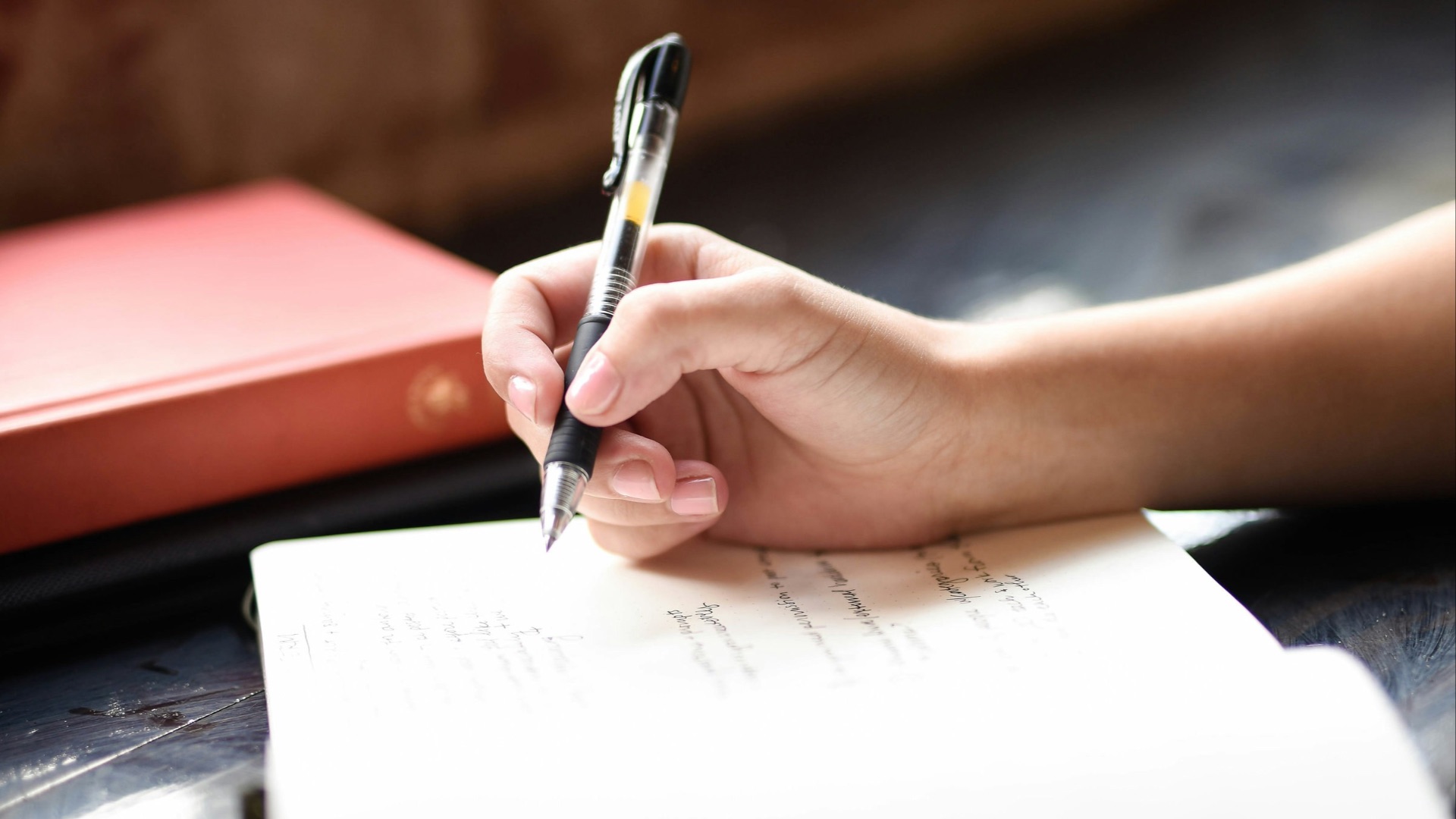 a person writing on a piece of paper with a pen