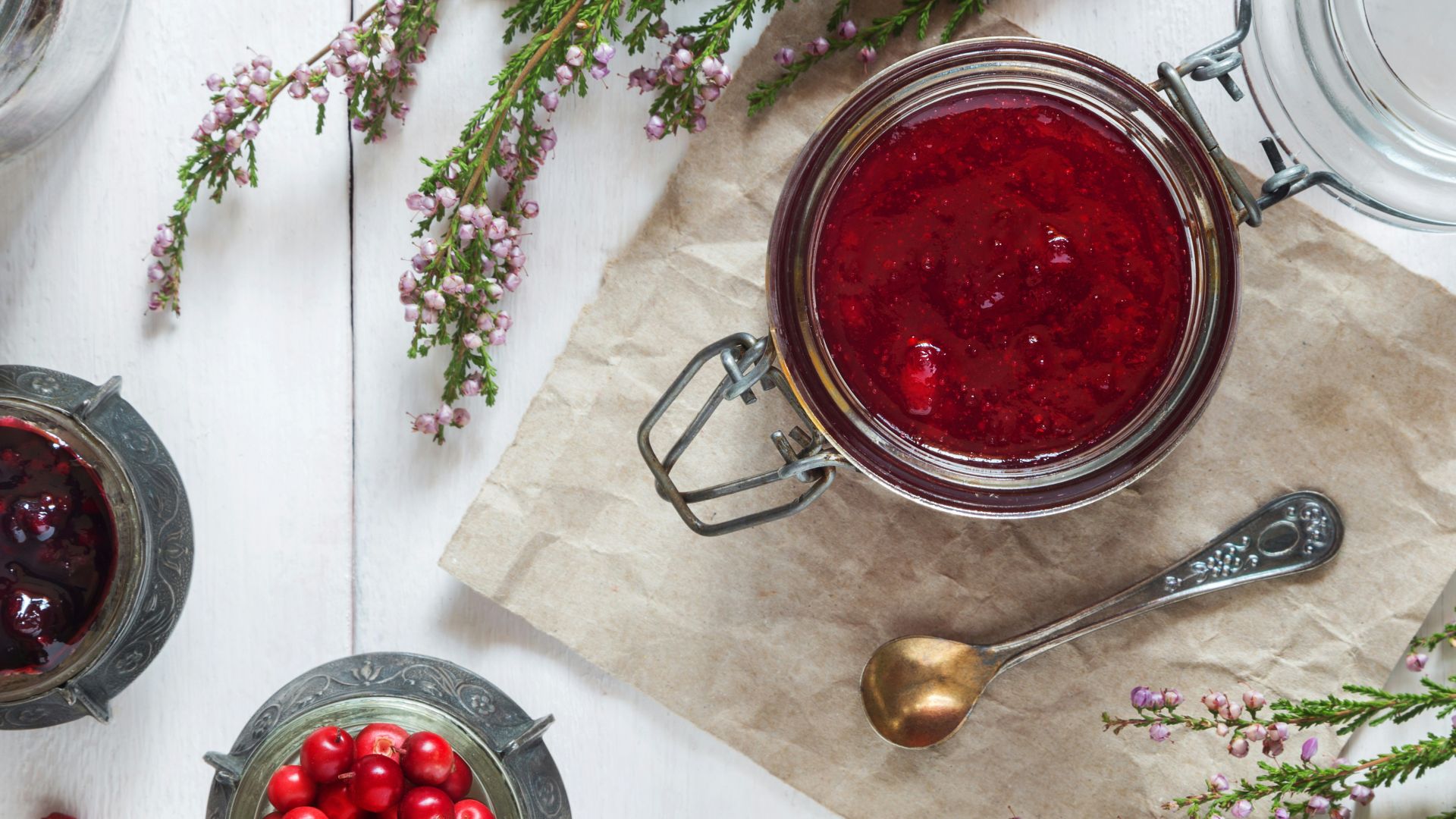 a table with a bowl of red berries and a spoon