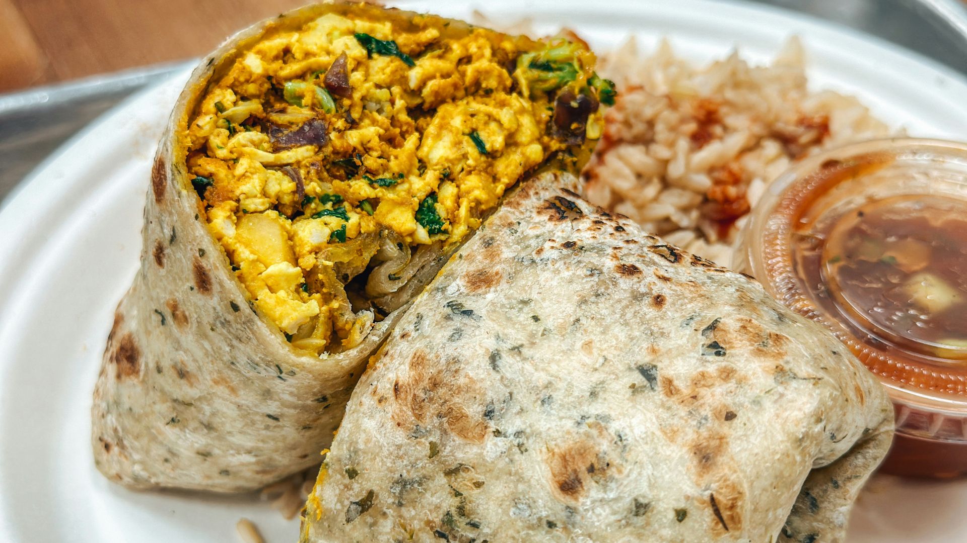a white plate topped with a burrito and rice