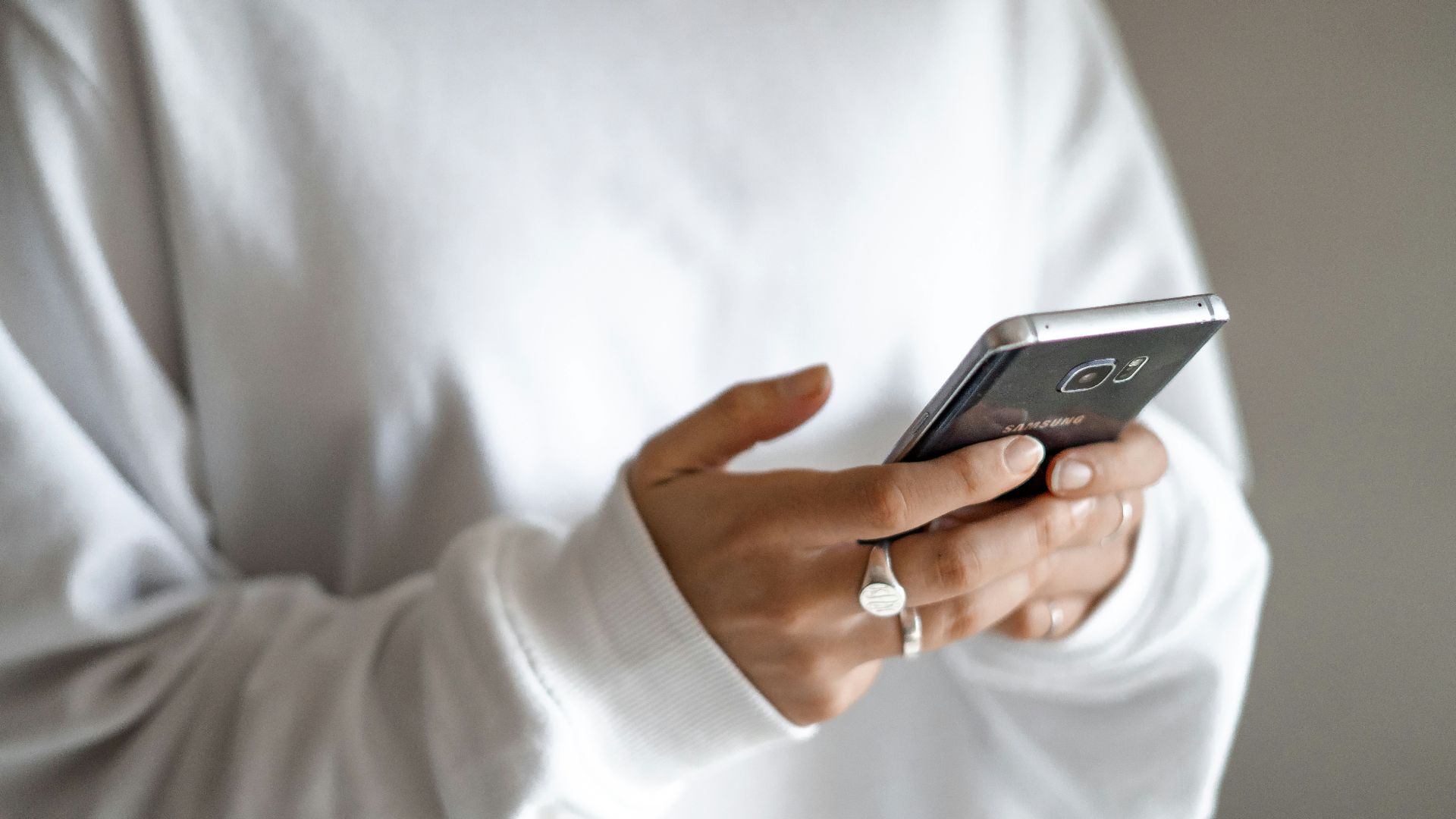 person in white long sleeve shirt holding black smartphone