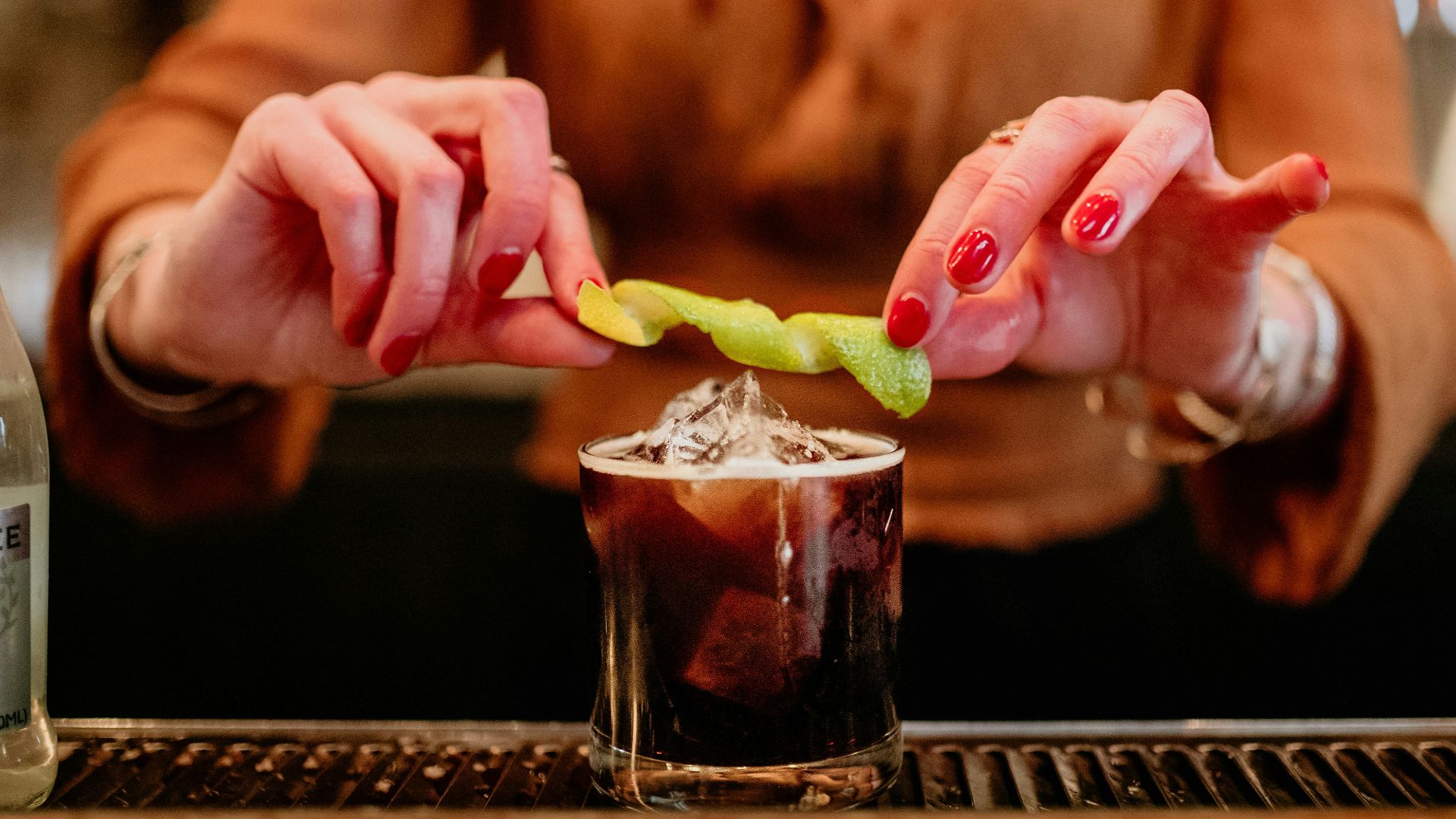 a woman holding a pickle over a drink