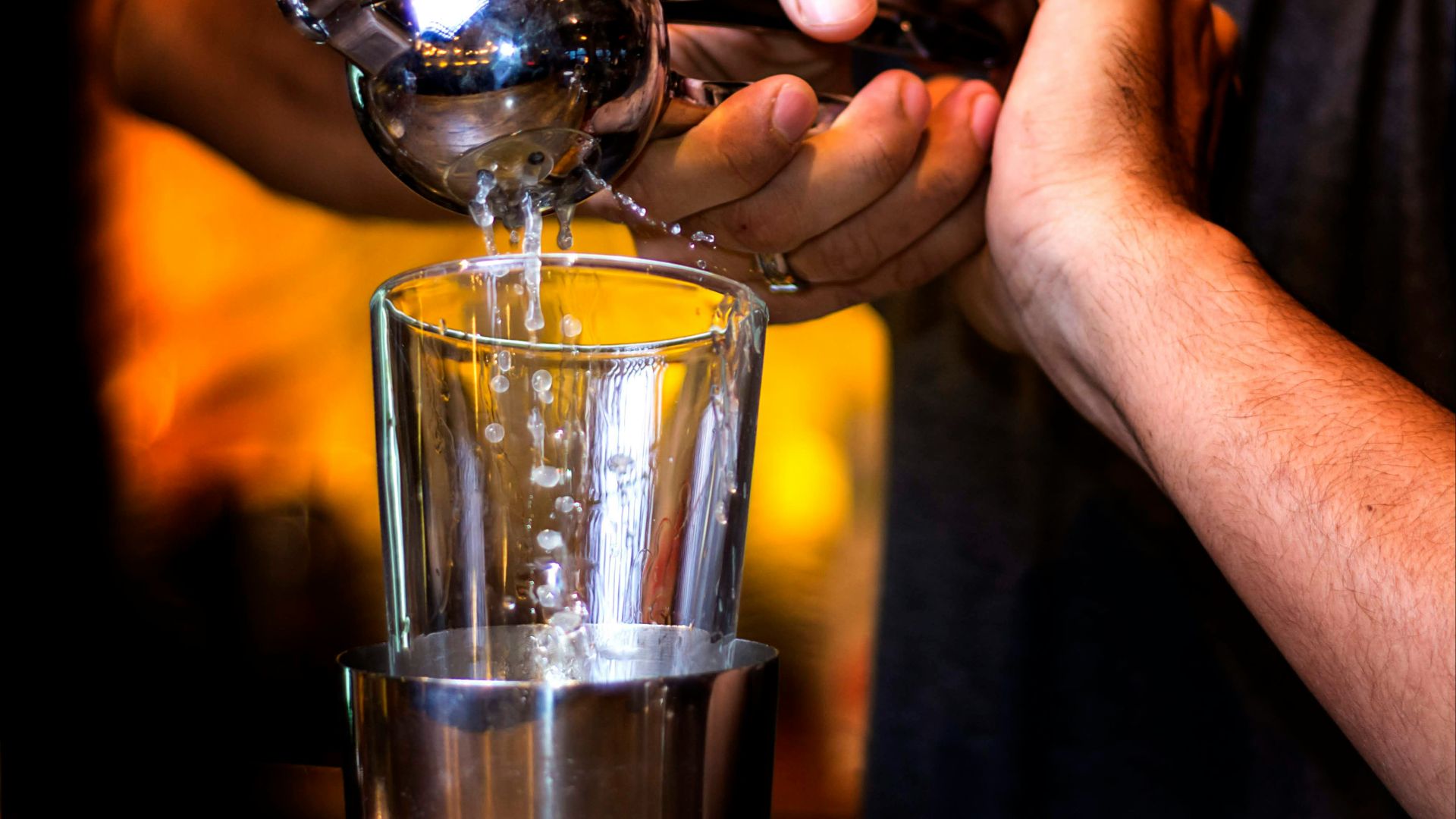 person pouring water on clear drinking glass