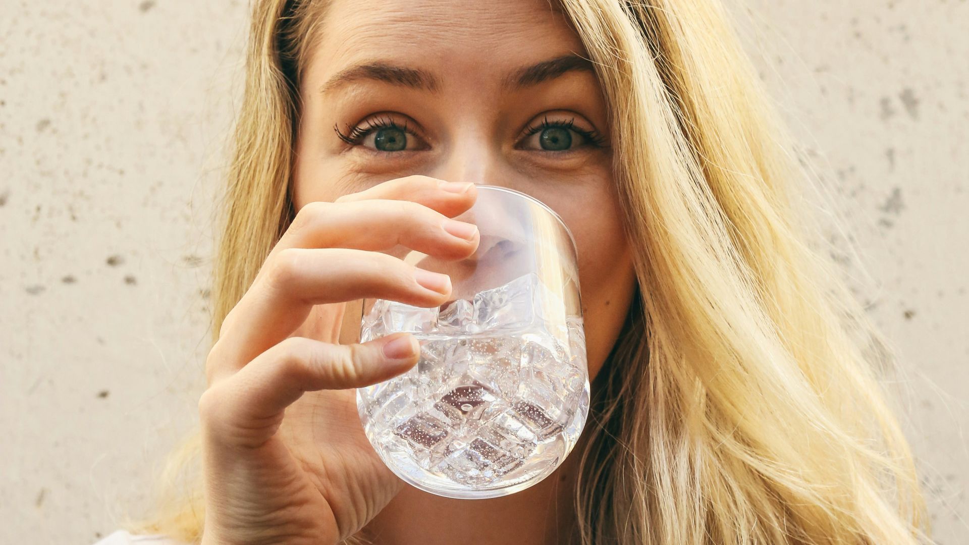 woman in white crew neck shirt drinking water