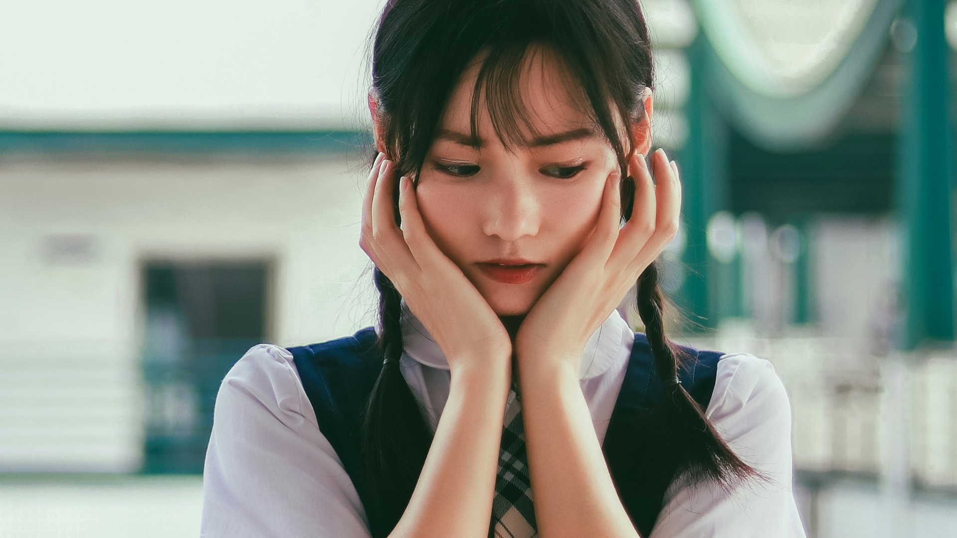 woman holding her face standing near white and green concrete building