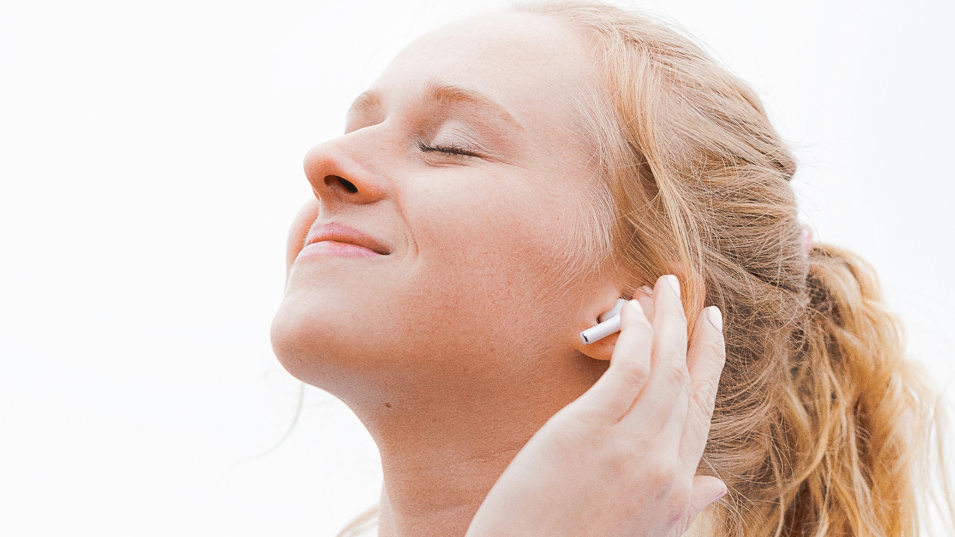 woman in white crew neck shirt covering her face with her hand