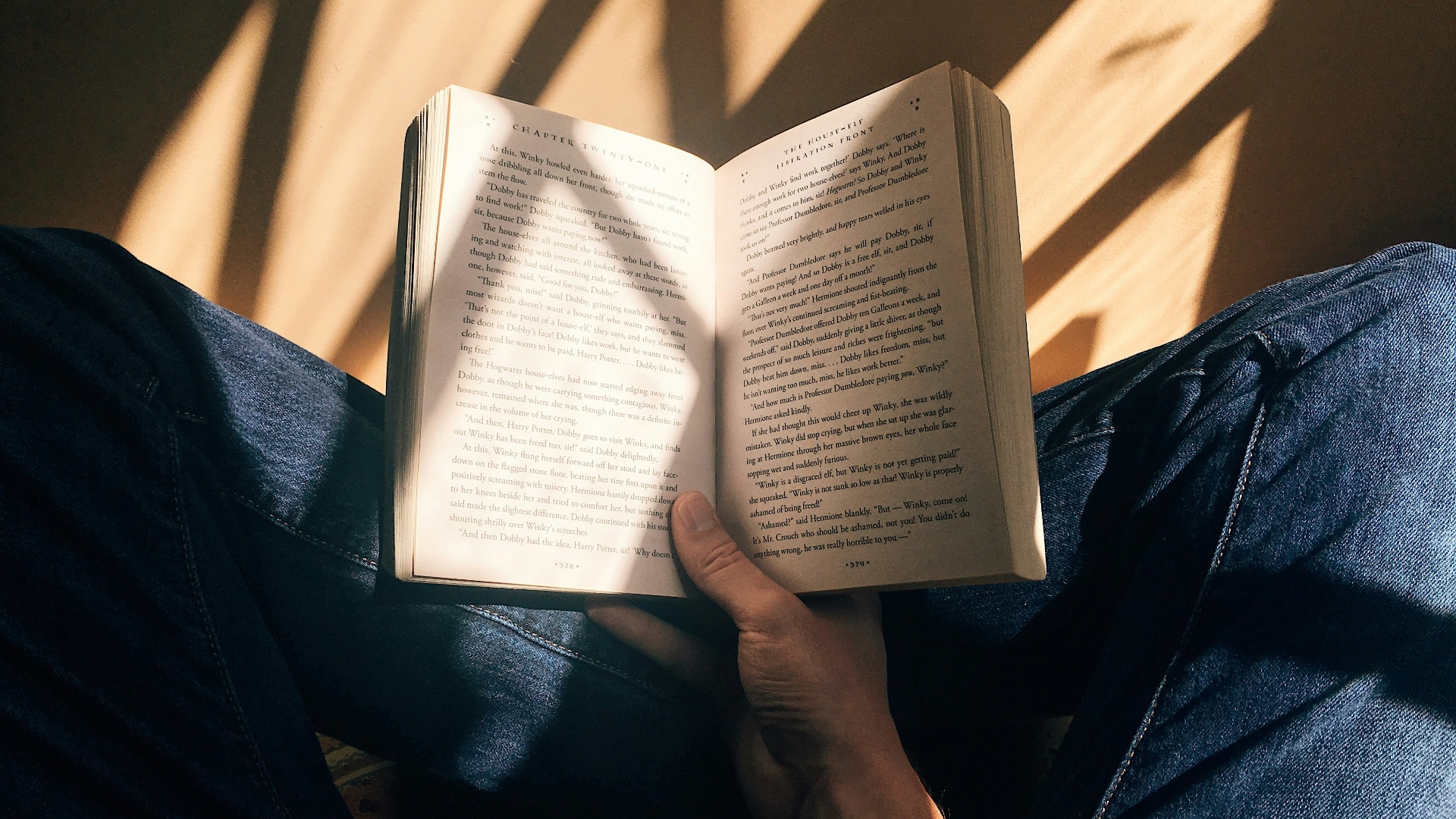 person holding book sitting on brown surface
