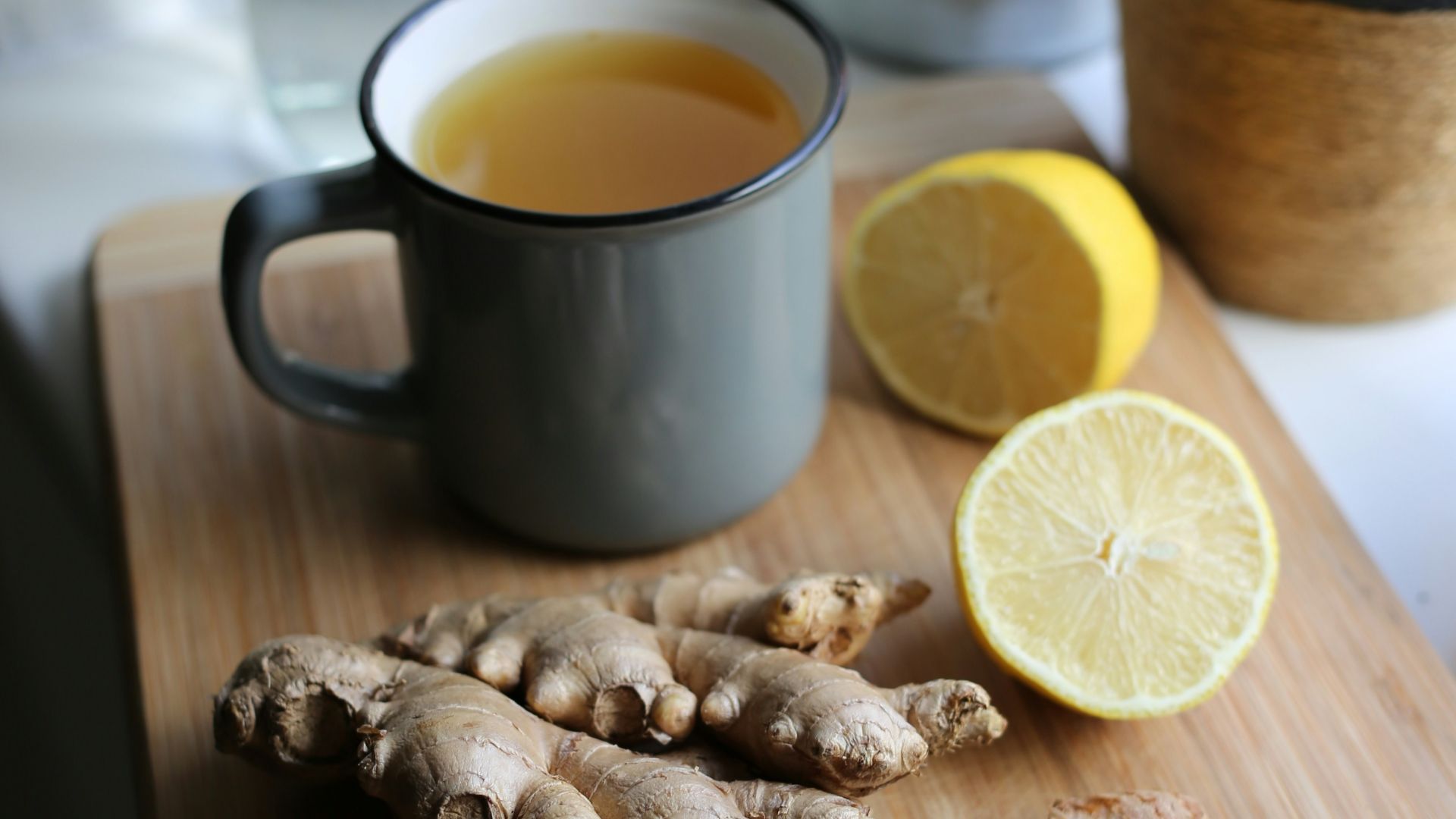 a wooden cutting board topped with sliced lemons and ginger