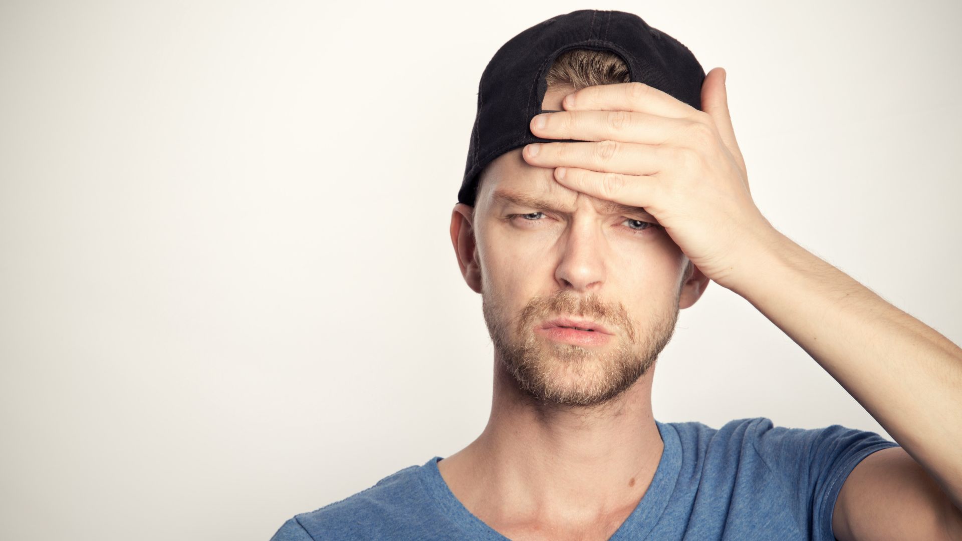 man in blue crew neck shirt covering his face