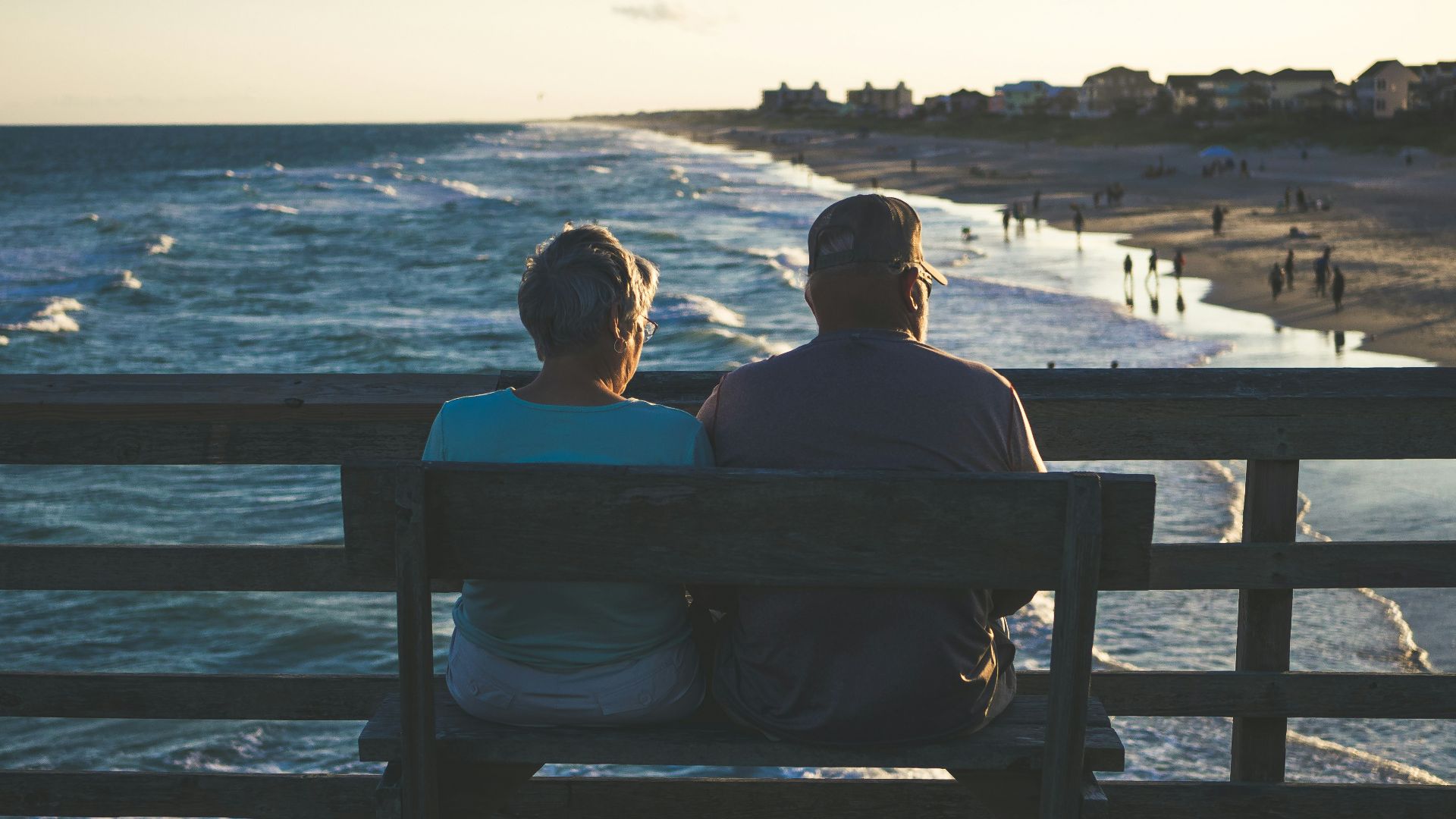 man and woman sitting on bench in front of beach