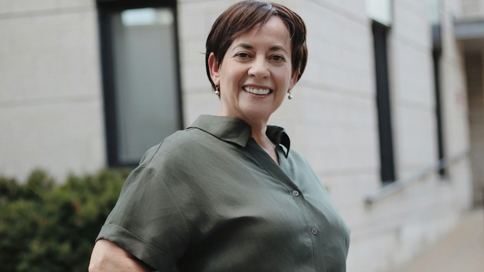 man in green button up t-shirt and white pants standing on road during daytime