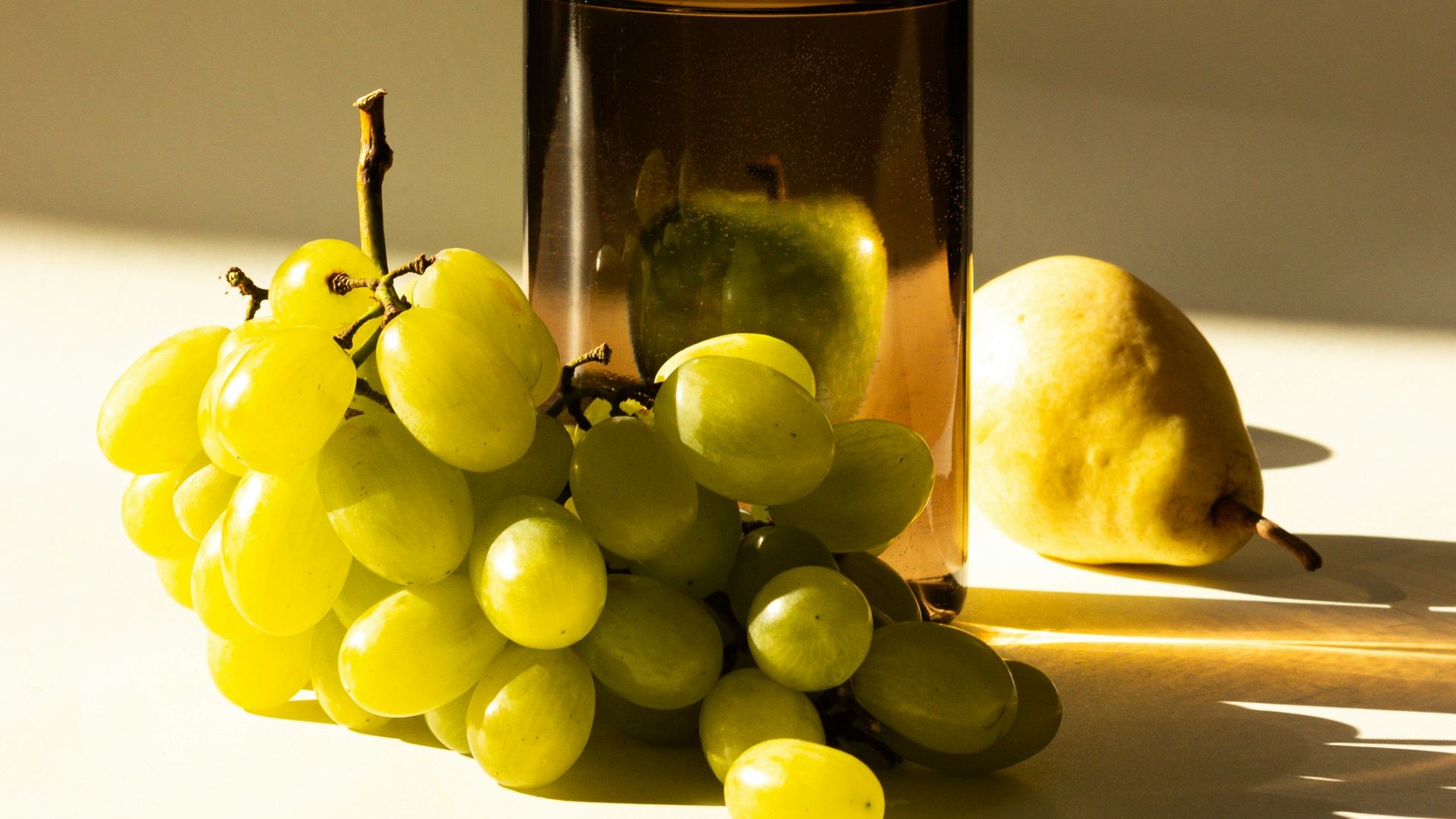 a bottle of wine next to a bunch of grapes
