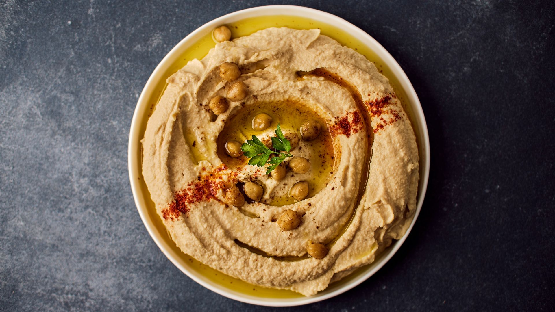 a bowl of hummus with a garnish on top
