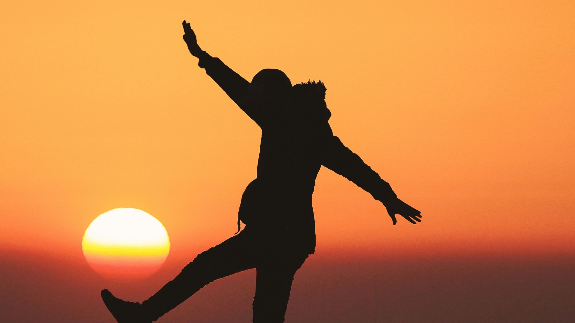 photo of silhouette photo of man standing on rock