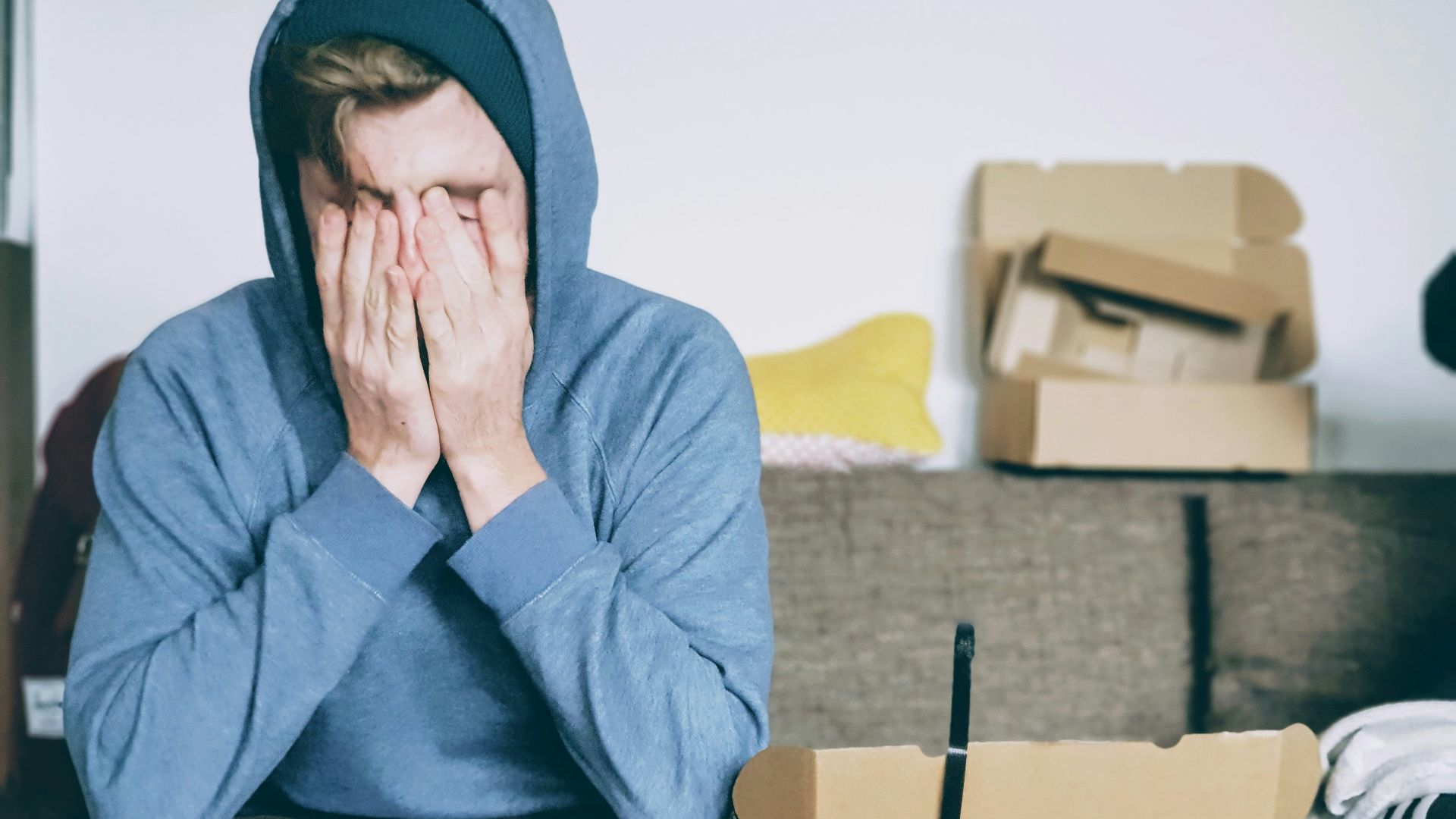 man covering face with both hands while sitting on bench
